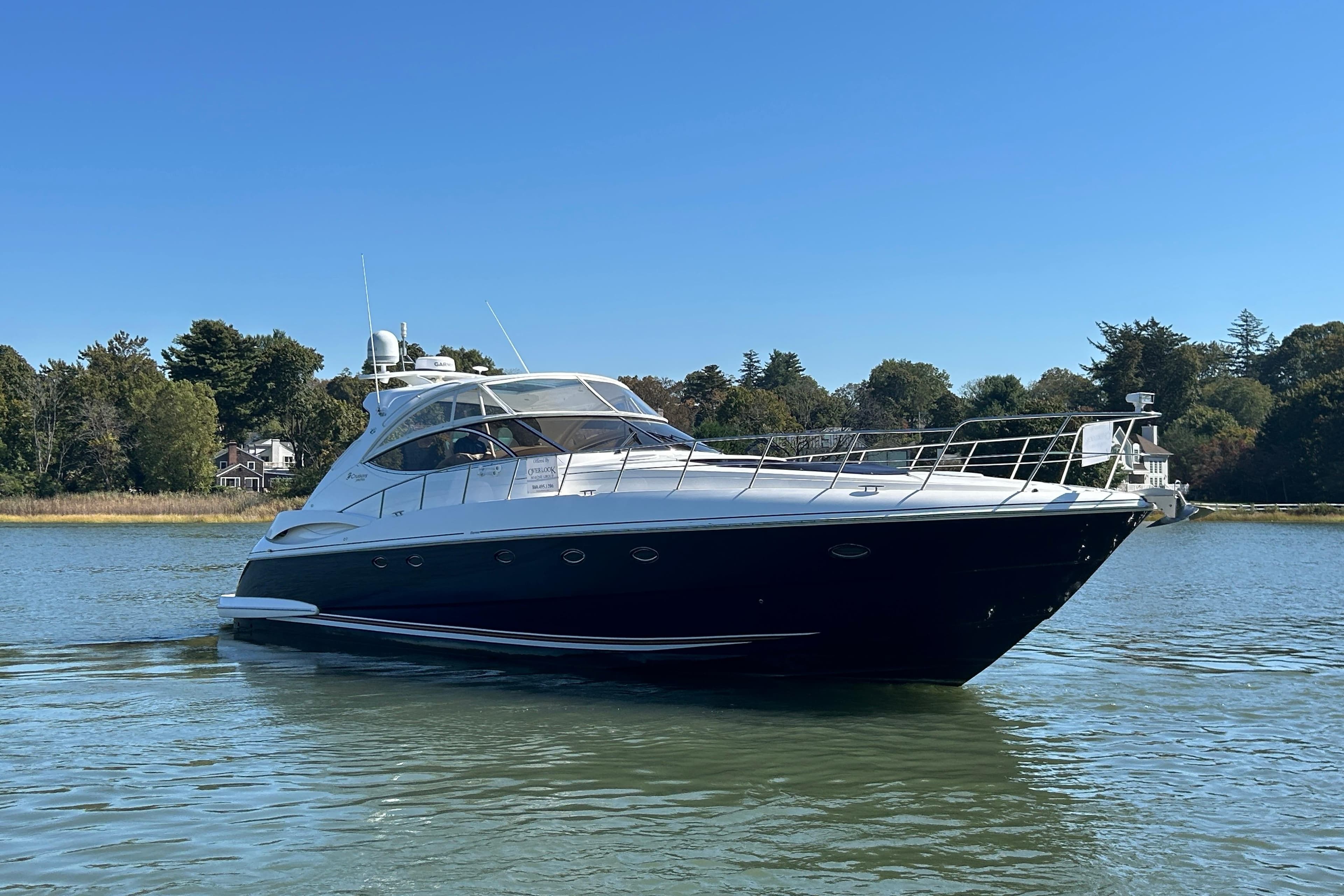 2003 Cruisers Yachts 540 Express on calm water, surrounded by trees and clear sky.