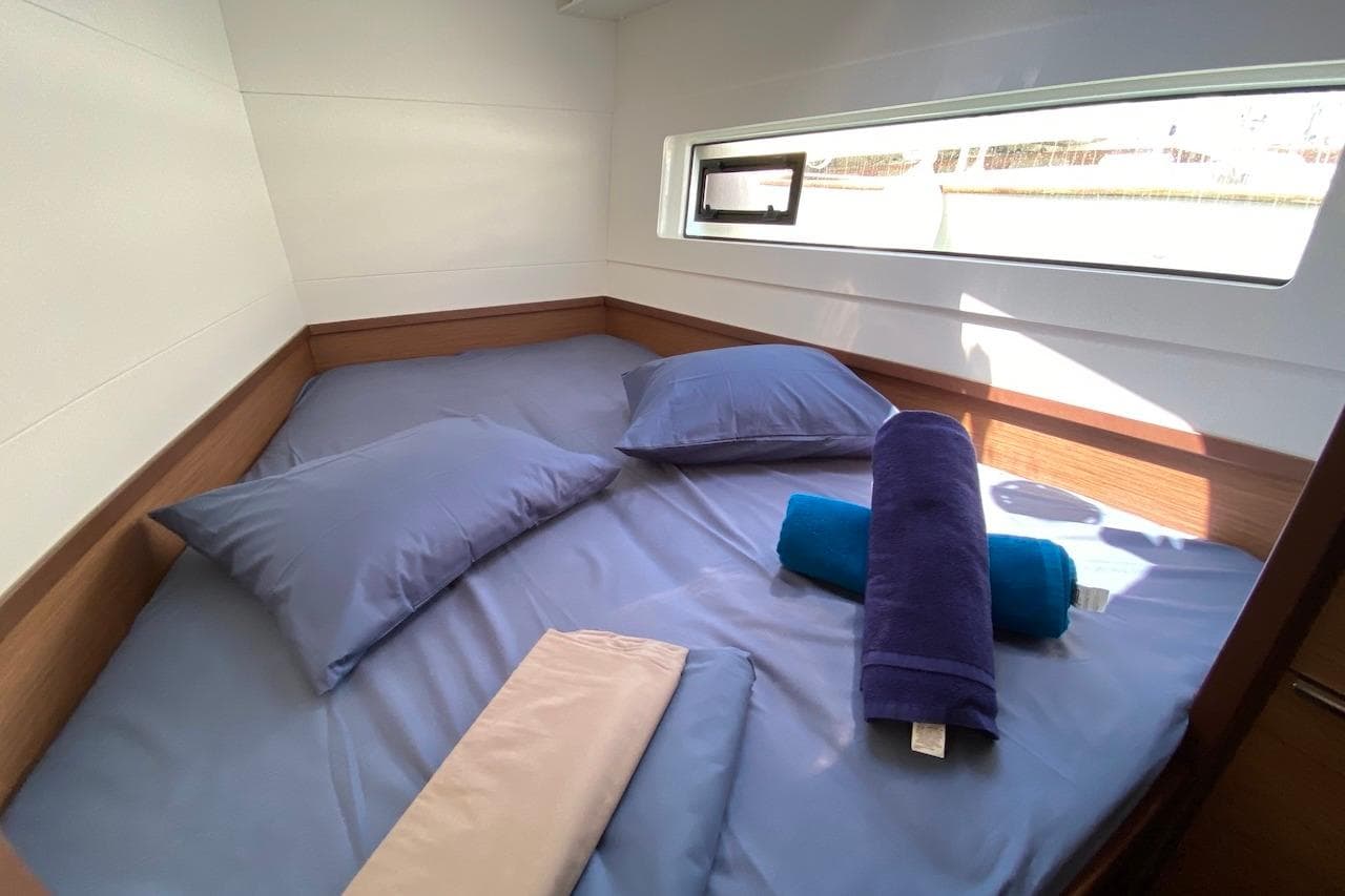 Cozy cabin interior of 2020 Lagoon 40 catamaran with blue bedding and towels.