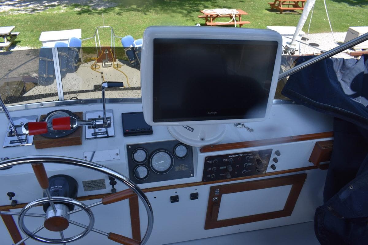 Control panel of a 1985 Marinette 39 Double Cabin boat with steering wheel and navigation equipment.