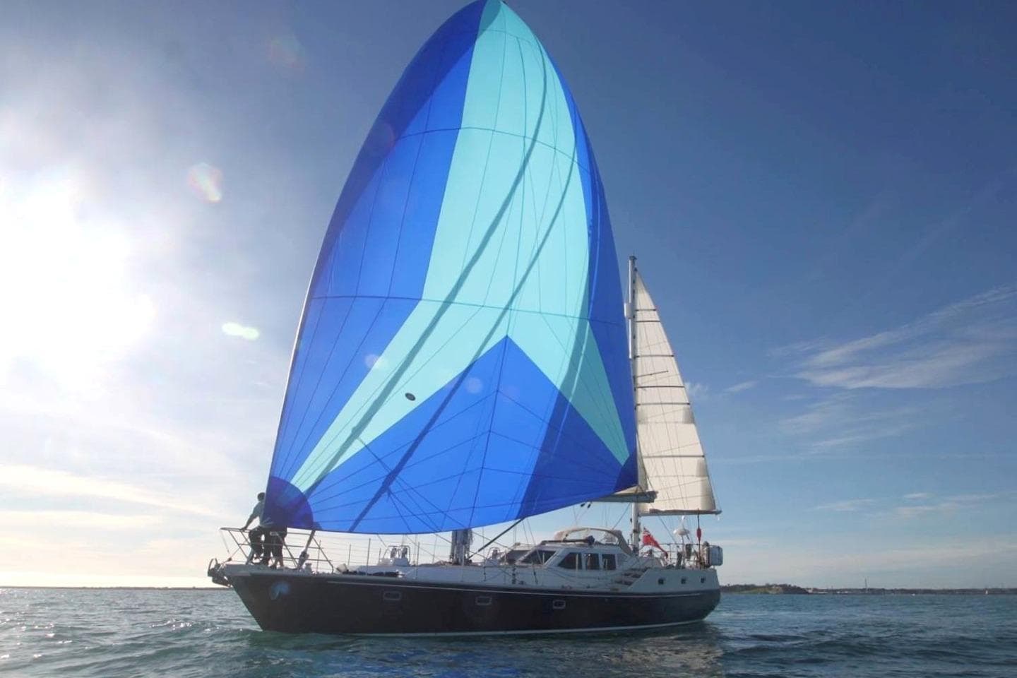 2016 Bruce Roberts 16.5m Expedition Yacht sailing with vibrant blue sails on open water.