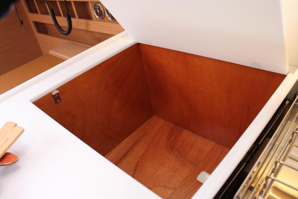 Open storage compartment on 2025 Jeanneau Sun Odyssey 440 yacht, featuring wooden interior.