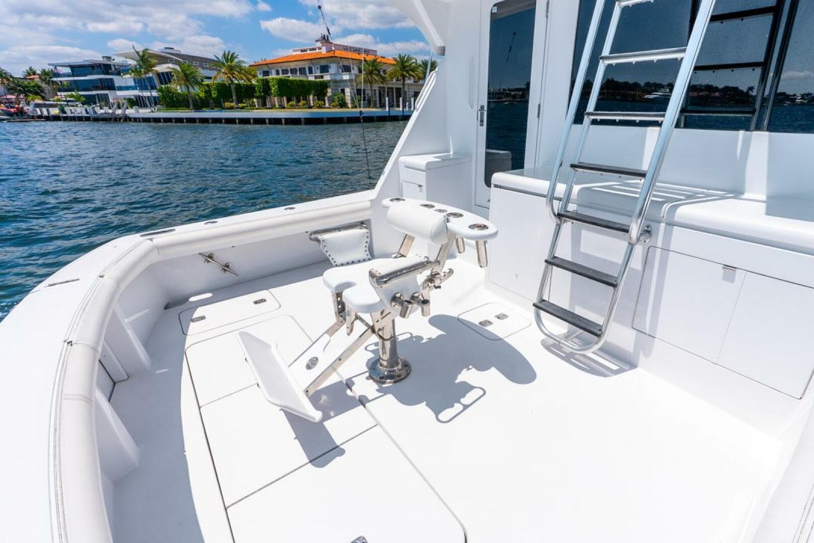 2005 Hatteras 50 Convertible Sportfish yacht deck with fishing chair and ladder by the water.