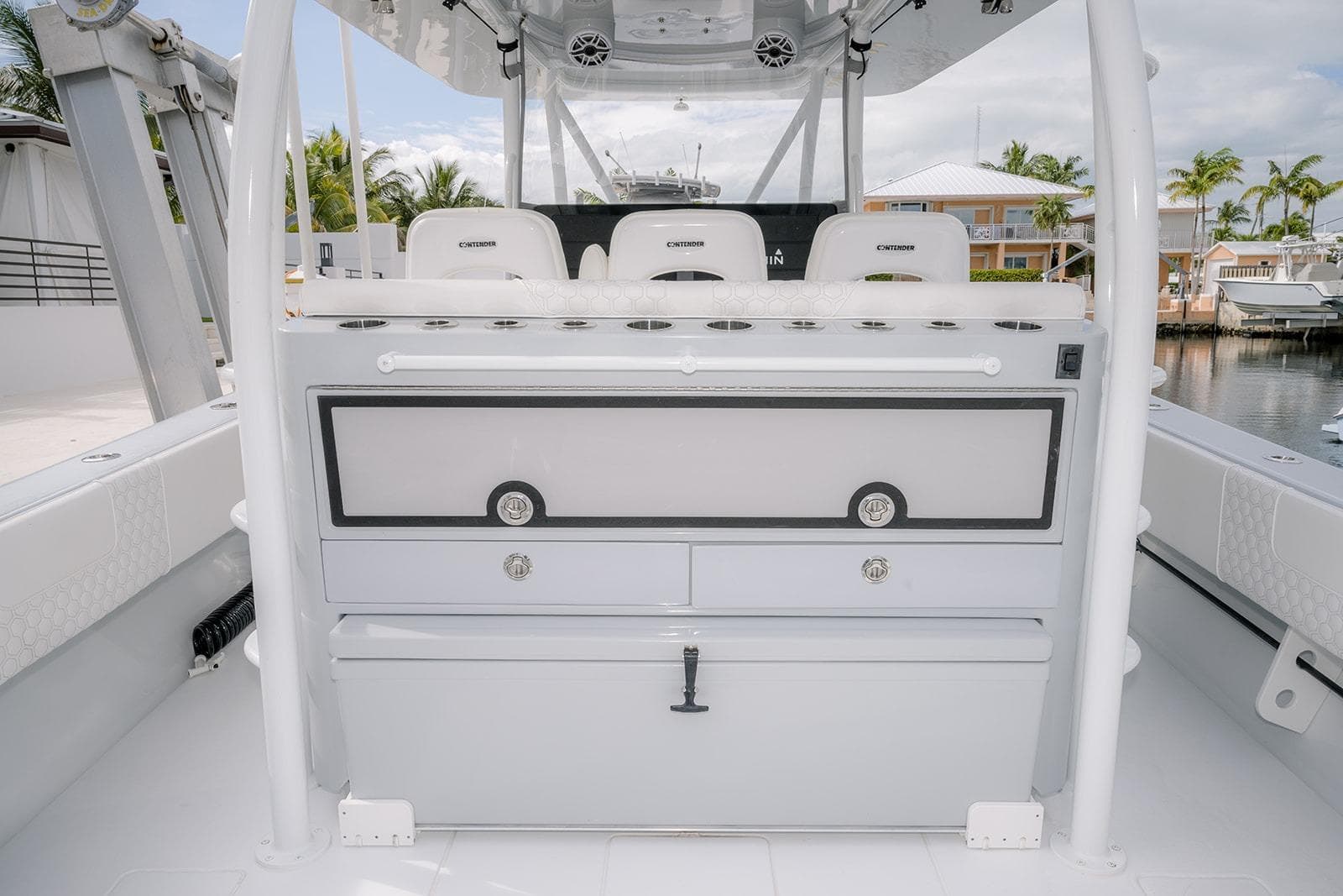 2024 Contender 44 ST boat interior with seating and storage, docked near waterfront homes.