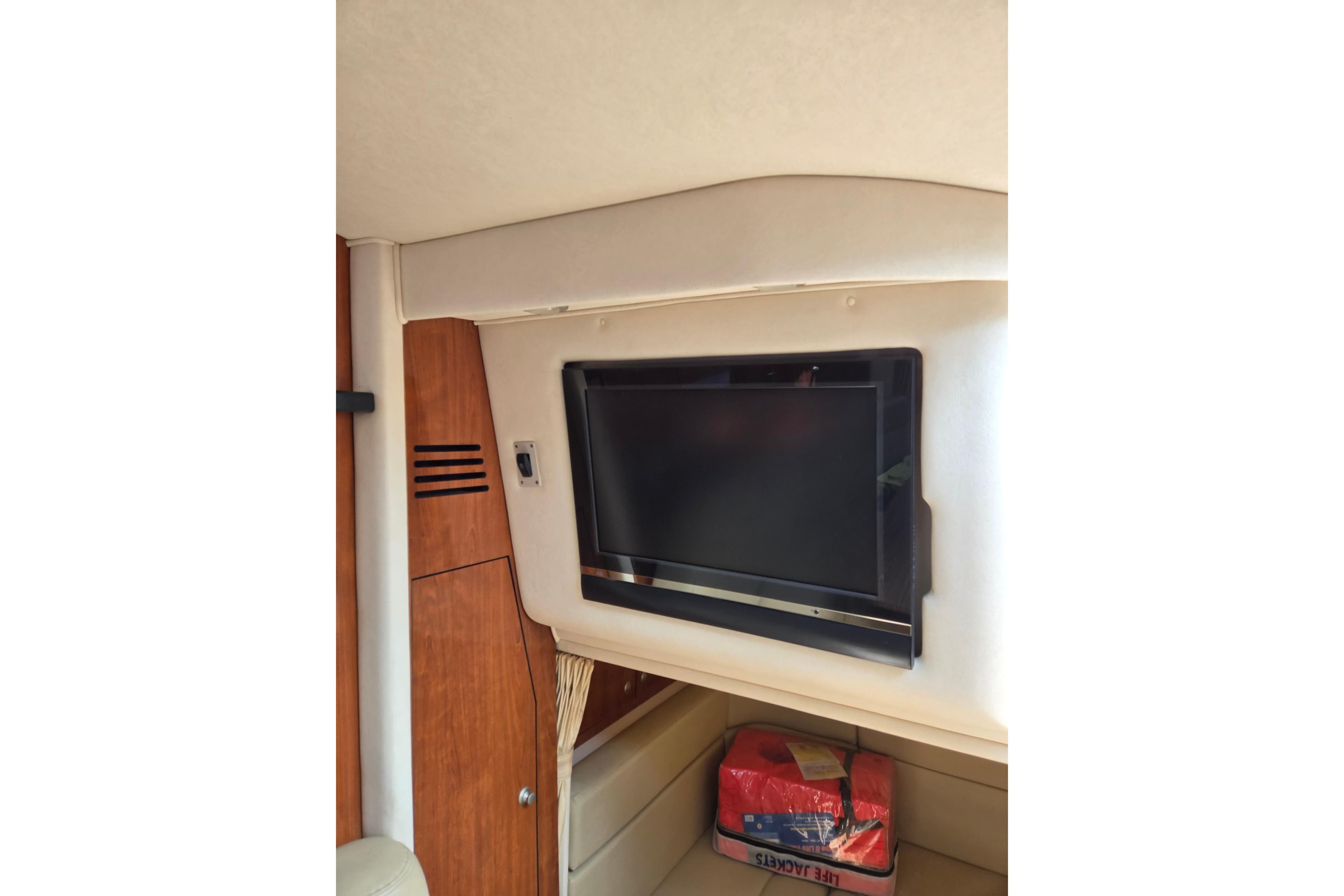 Interior of 2006 Sea Ray Sundancer 320 with mounted TV and storage area.