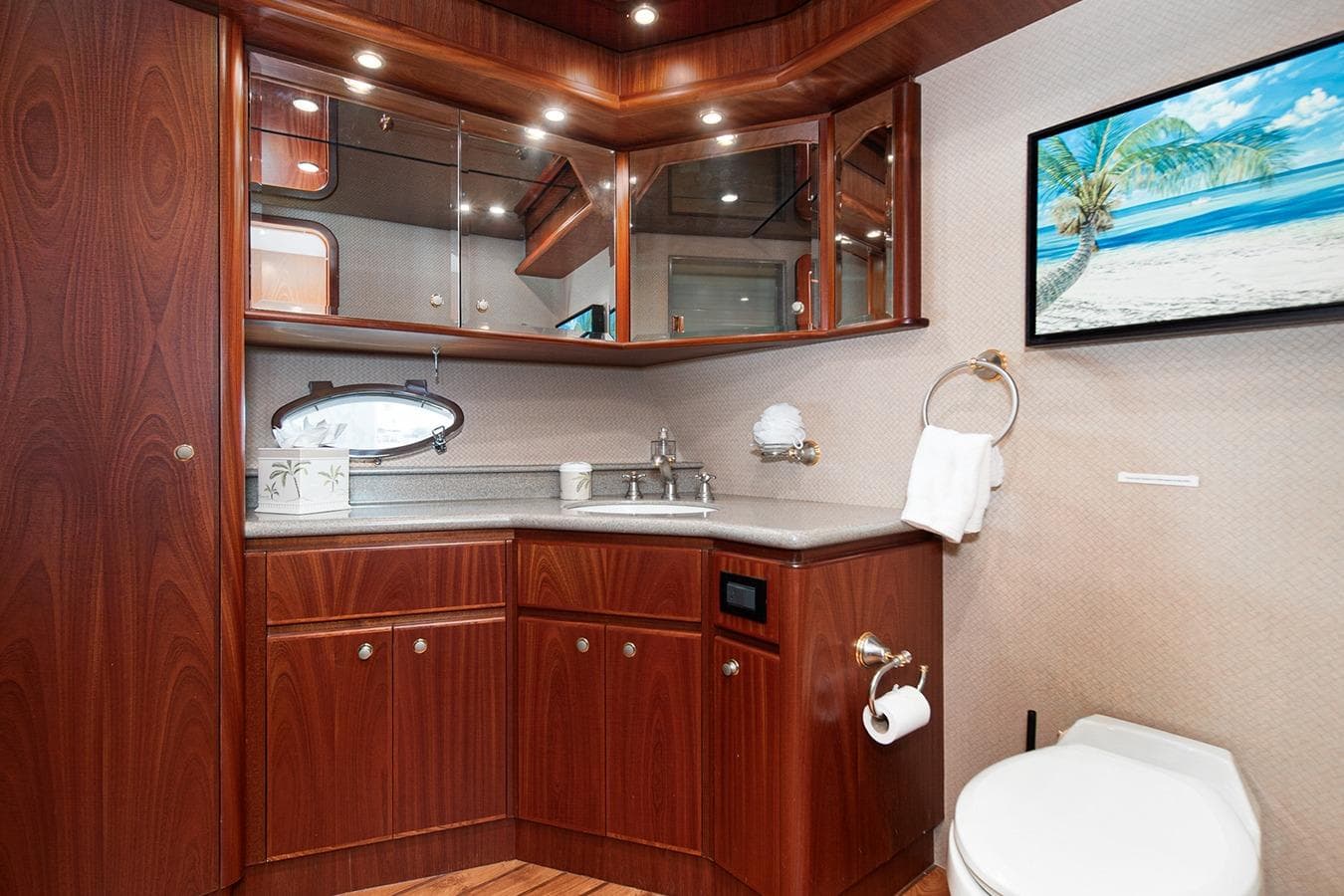 Luxurious 2003 West Bay Sonship yacht bathroom with wood cabinetry and beach artwork.