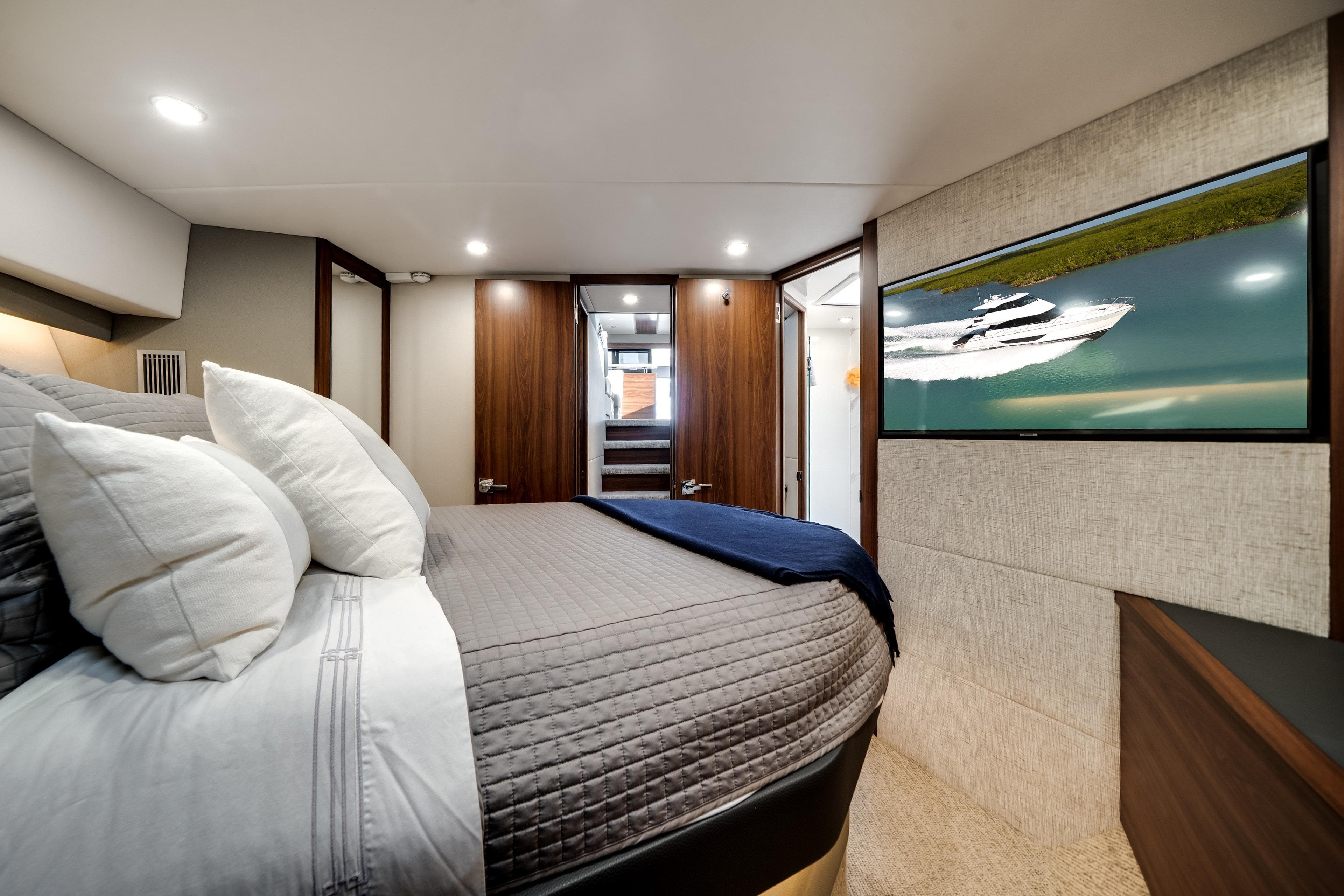 Luxurious 2024 Maritimo M55 yacht bedroom with modern decor and wall-mounted TV.