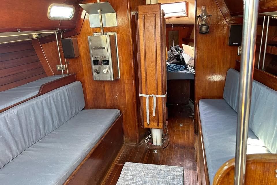 Interior of 1982 Ericson 33 sailboat with wooden paneling and blue cushions.