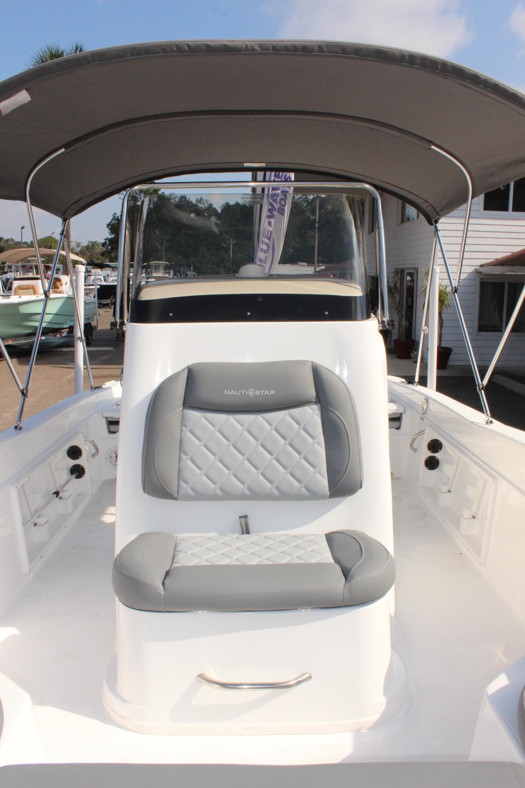 2025 NauticStar 211 Hybrid boat with cushioned seating and canopy.