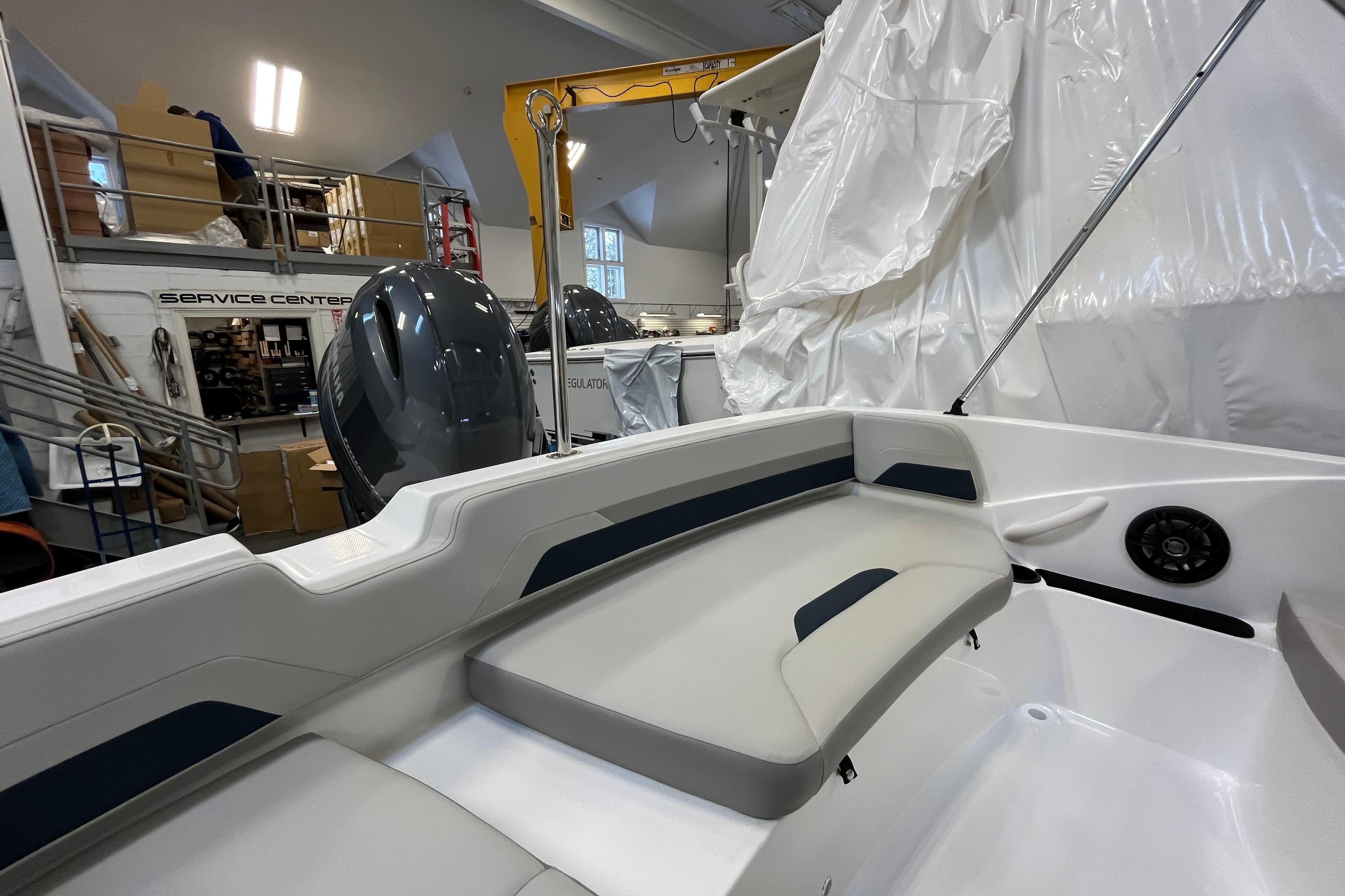 2026 Hurricane SunDeck Sport 185 OB boat interior in a service center, showcasing seating and motor.