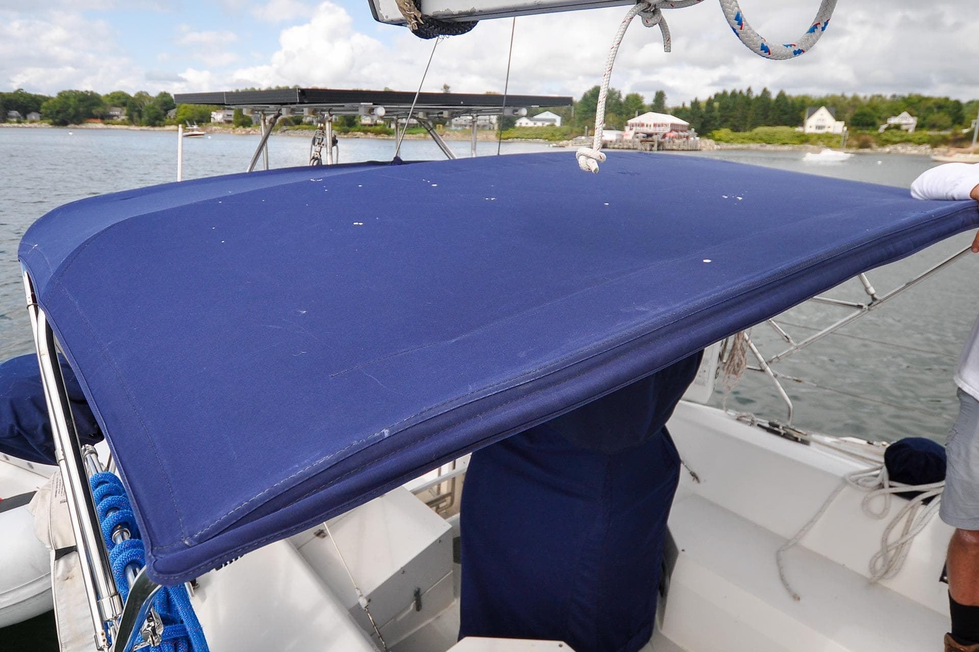Blue bimini top on a 1993 Catalina 42 sailboat, docked near a scenic shoreline.