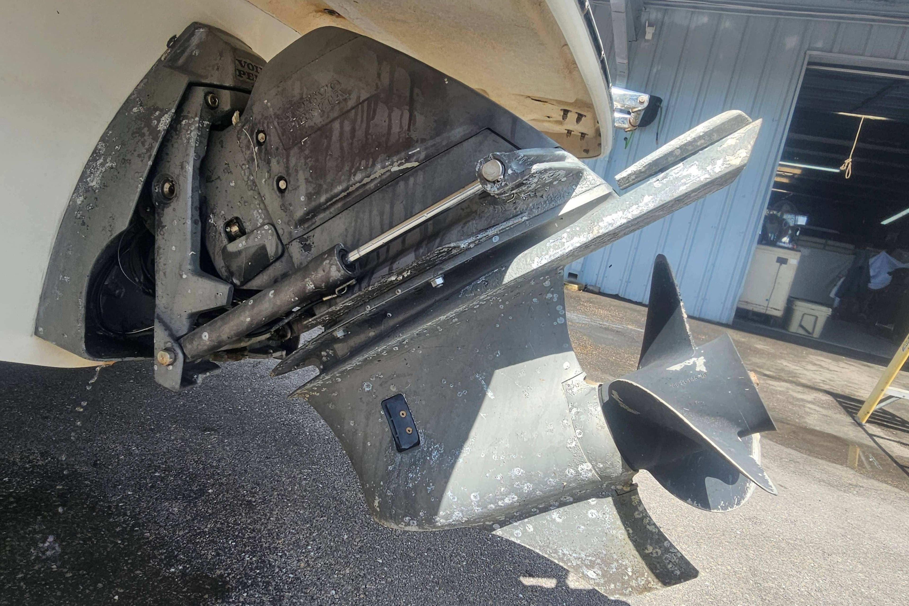 Close-up of a 2008 Glastron GT 205 boat's propeller and outdrive in a garage setting.