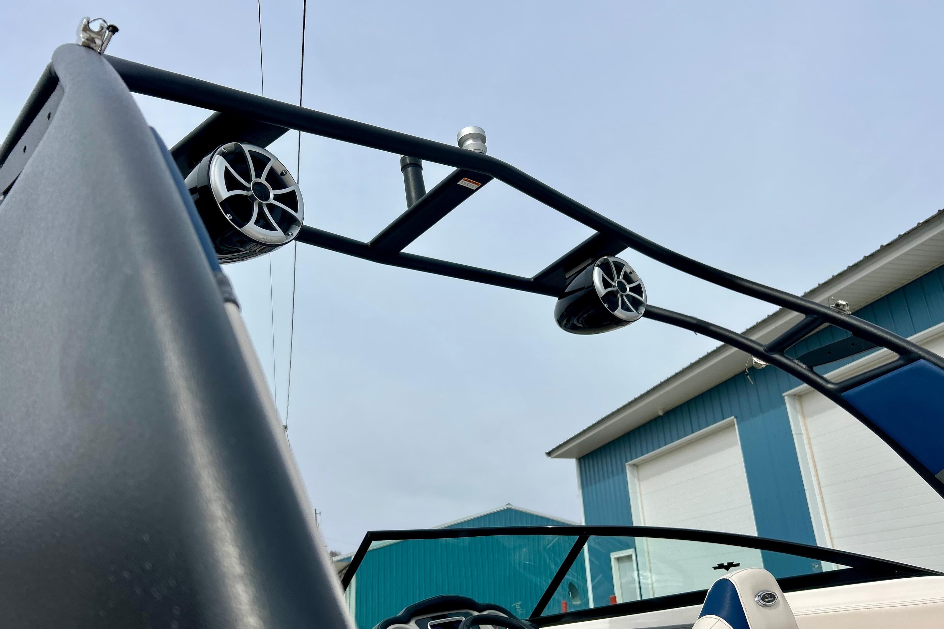 2017 Chaparral 203 Vortex boat with speakers on wakeboard tower, blue building background.