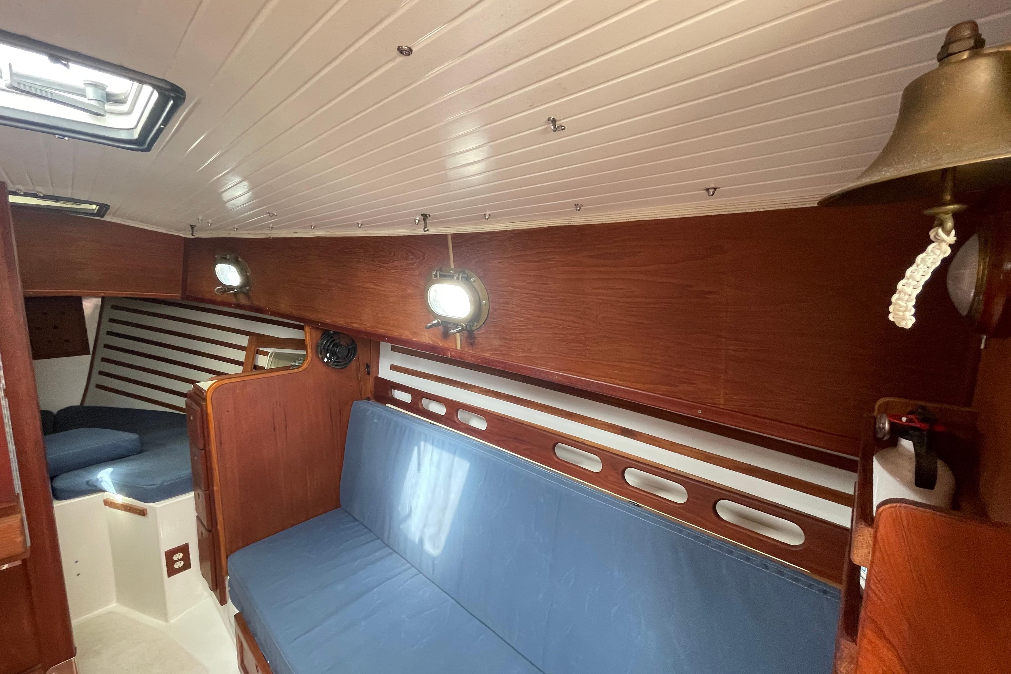 Interior of 1987 Com-Pac 27 sailboat with wooden paneling and blue seating.
