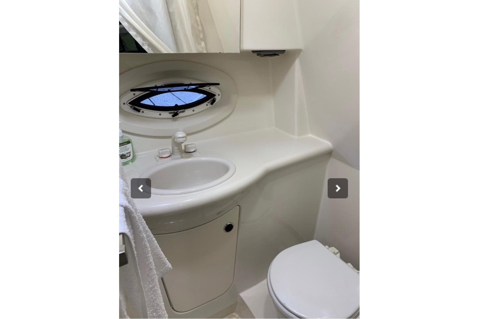 Compact bathroom in 2008 Bayliner 265 boat with sink, toilet, and porthole window.