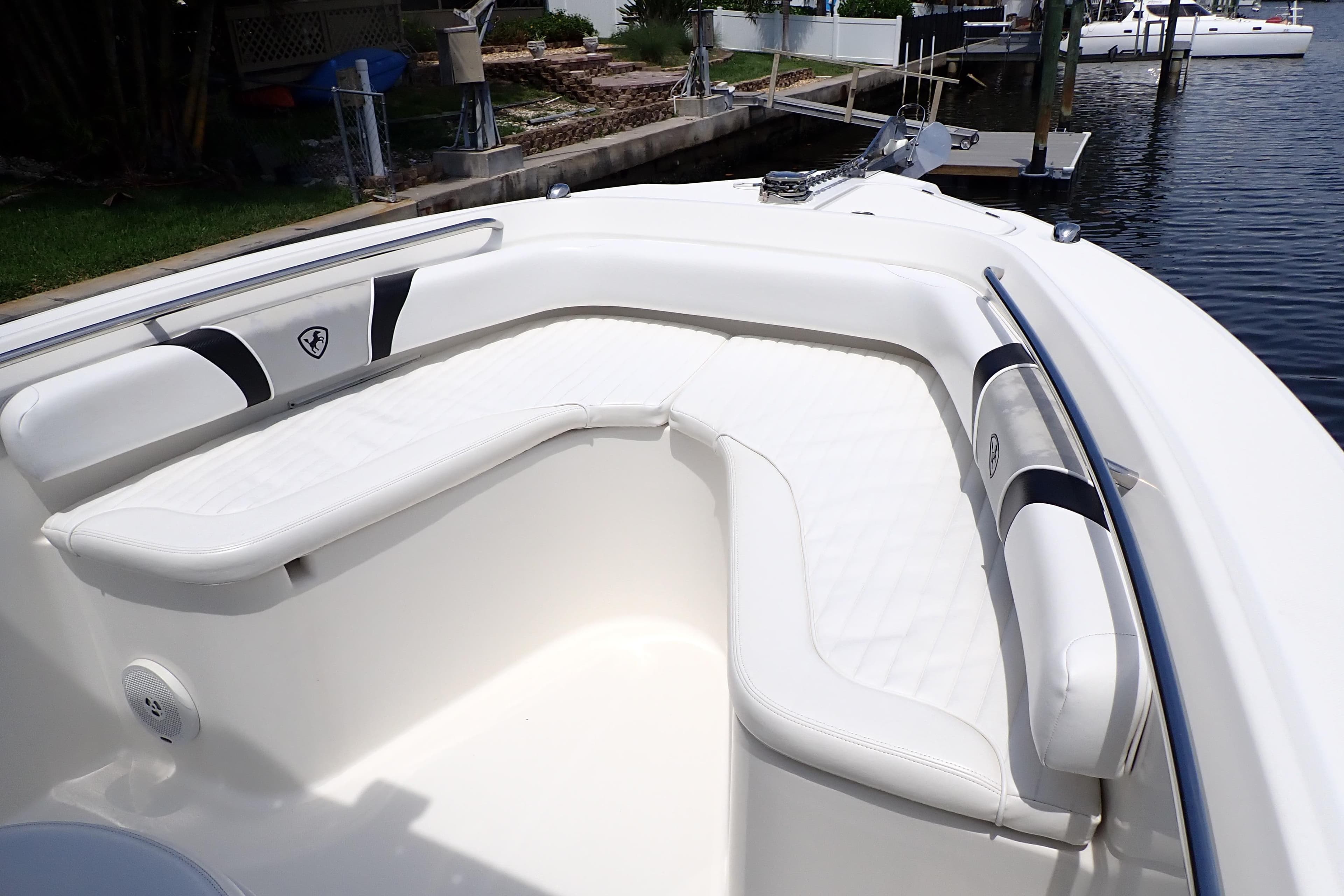 2015 Century 2301 Center Console boat with white cushioned seating, docked by the water.