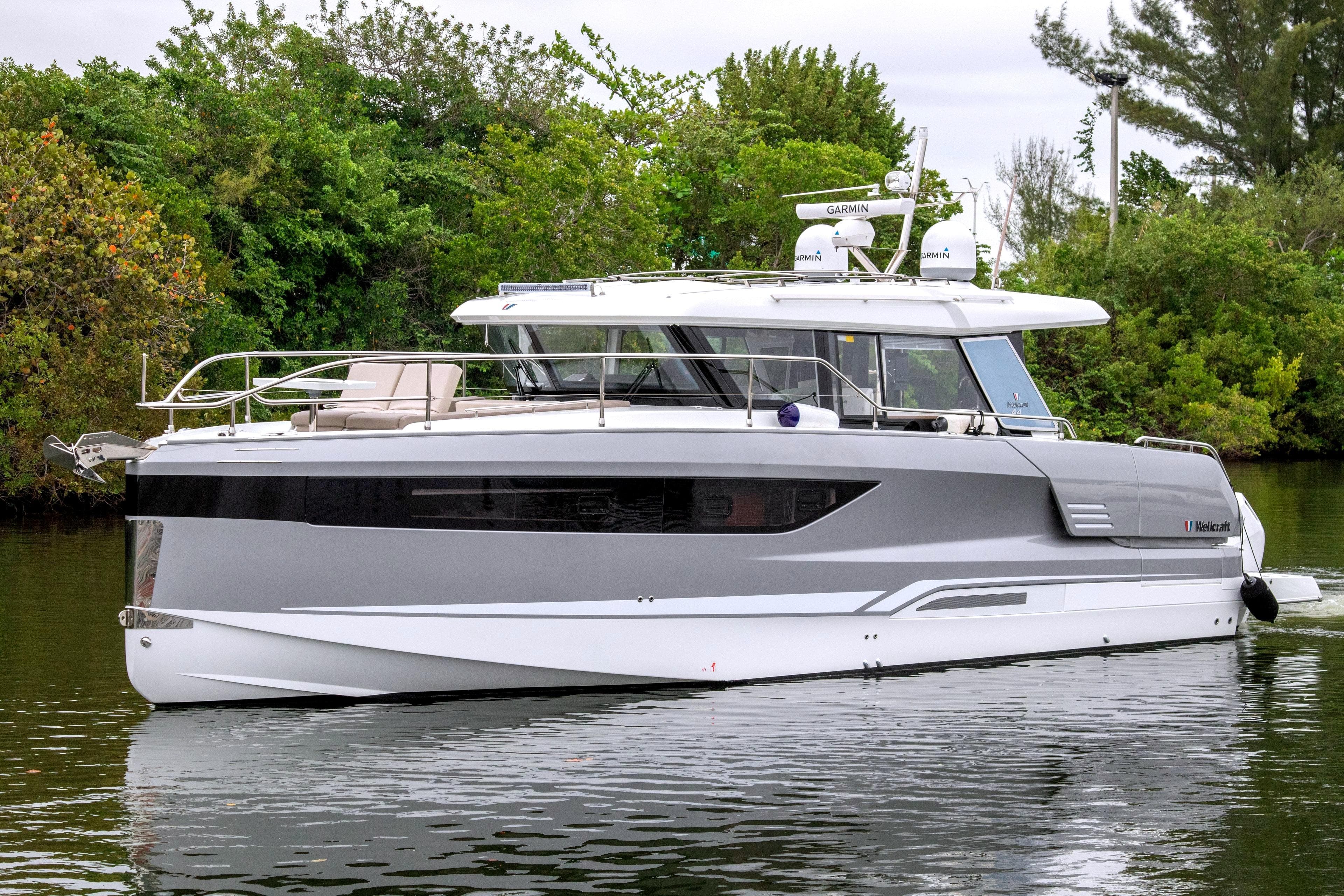 2026 Wellcraft 44 Explorer yacht on calm water, surrounded by lush greenery.