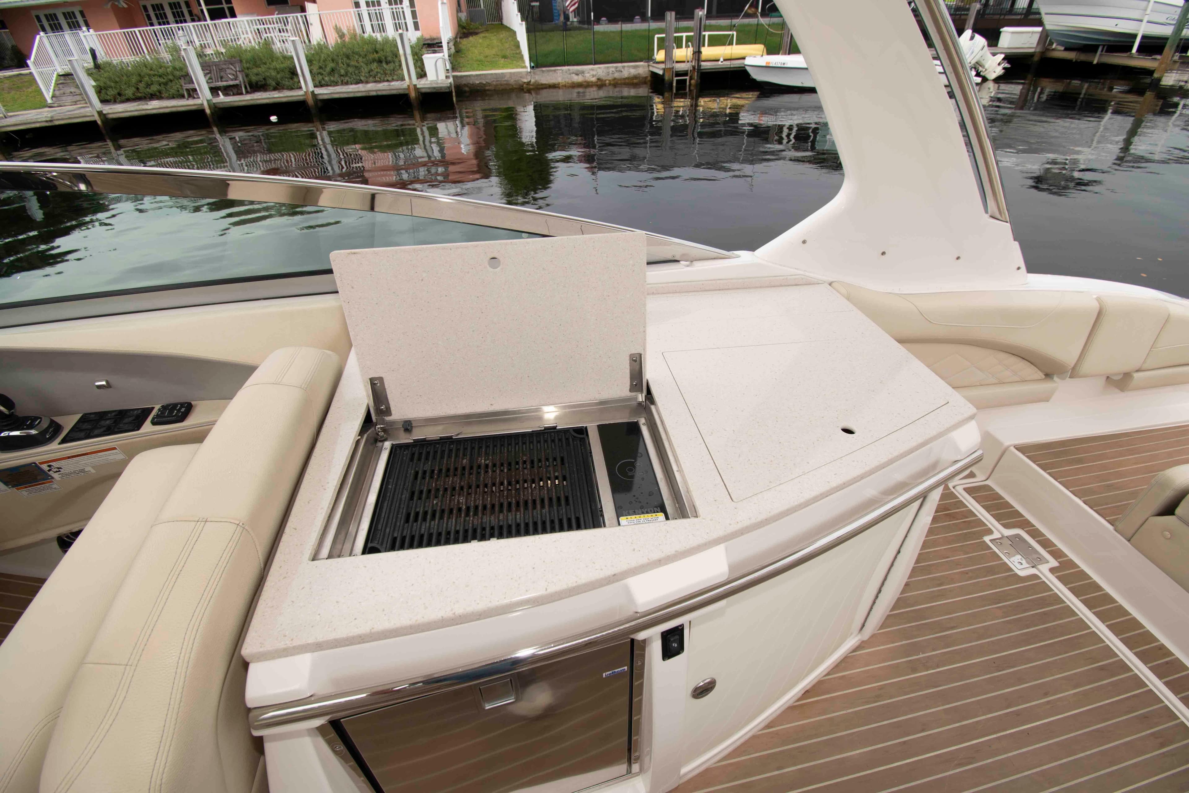 2019 Regal 33 OBX boat with onboard grill and seating area by the water.
