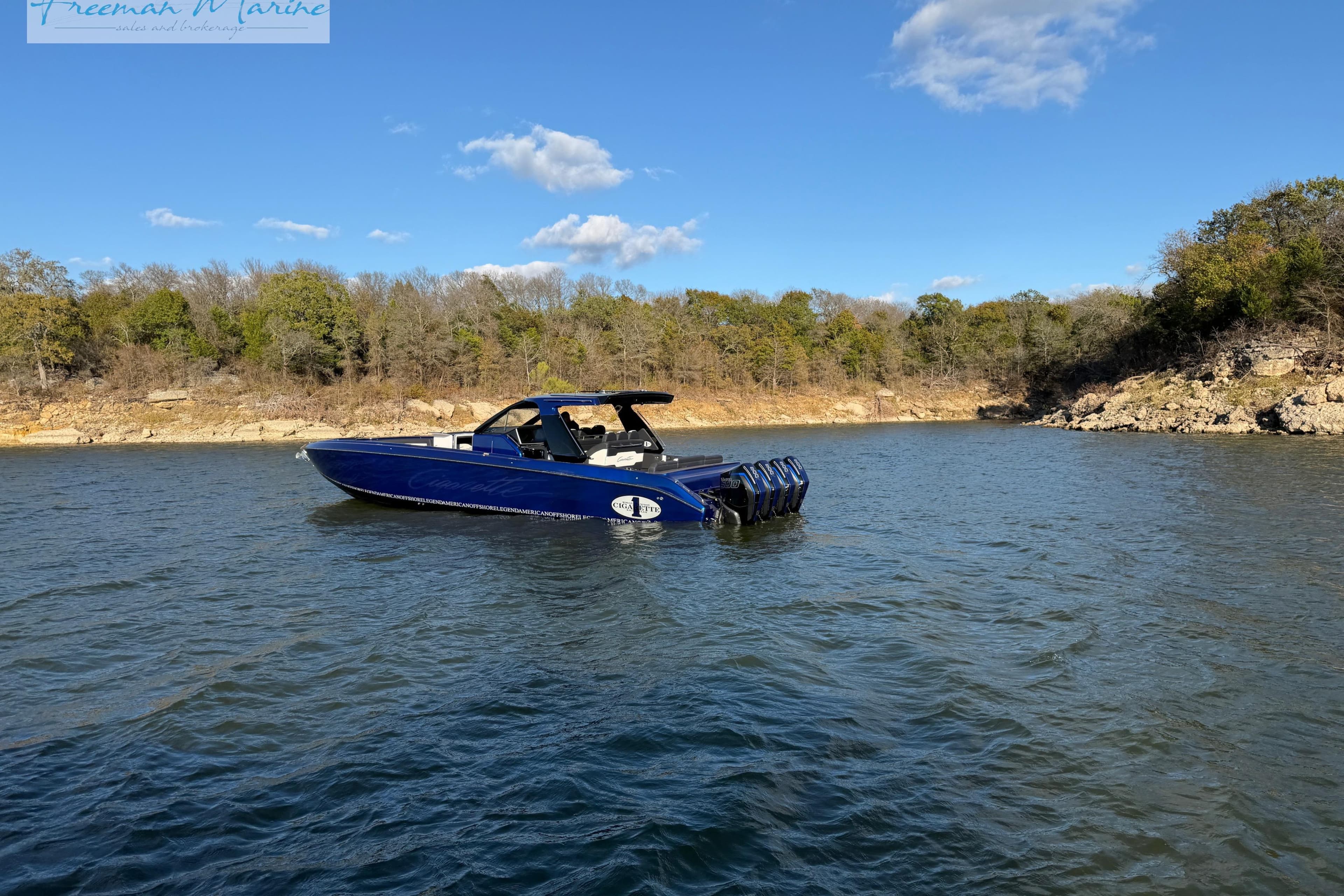 2024 Cigarette 41' Nighthawk boat on a serene lake with wooded shoreline.