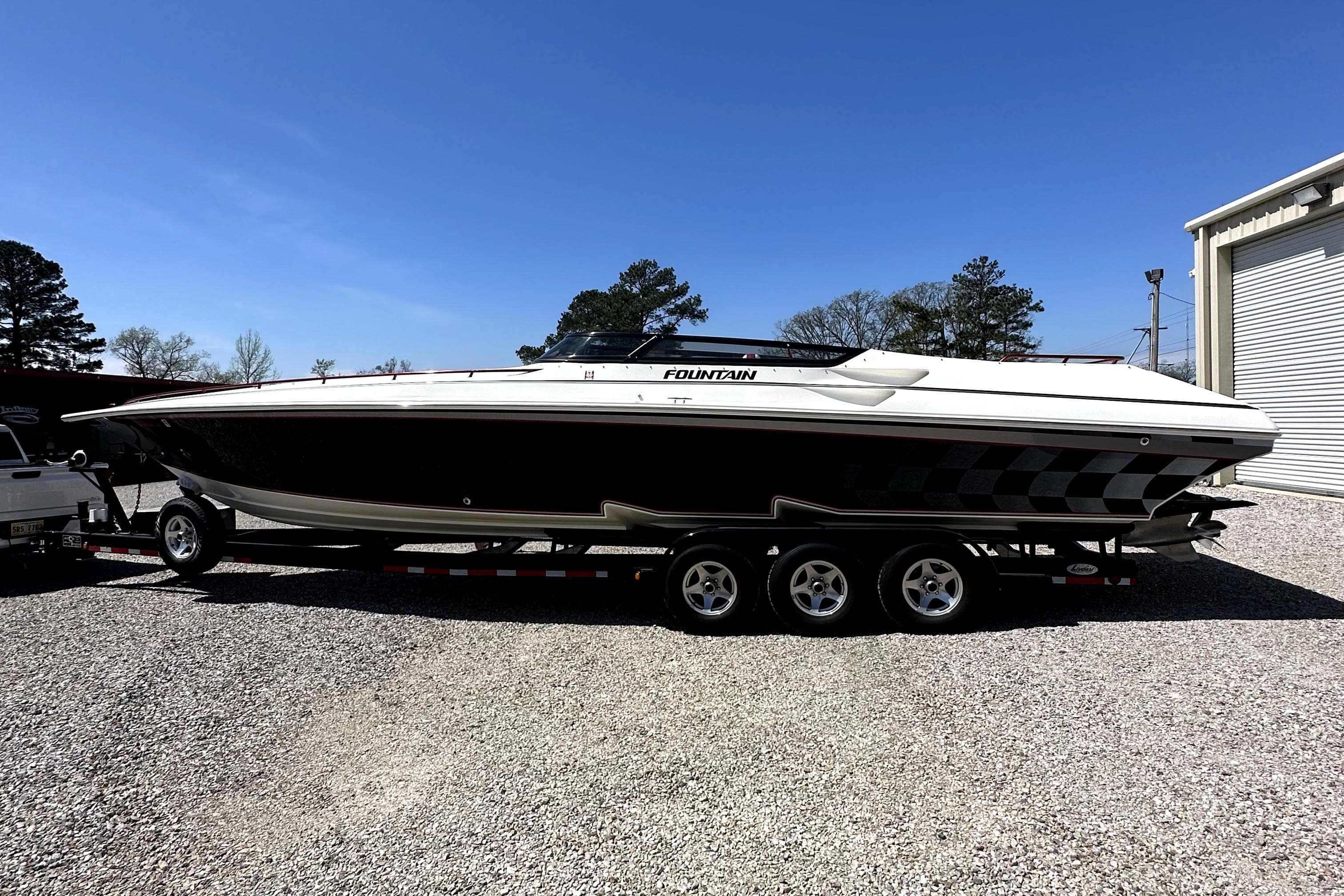 2003 Fountain 38 Lightning speedboat on a trailer in a gravel lot.