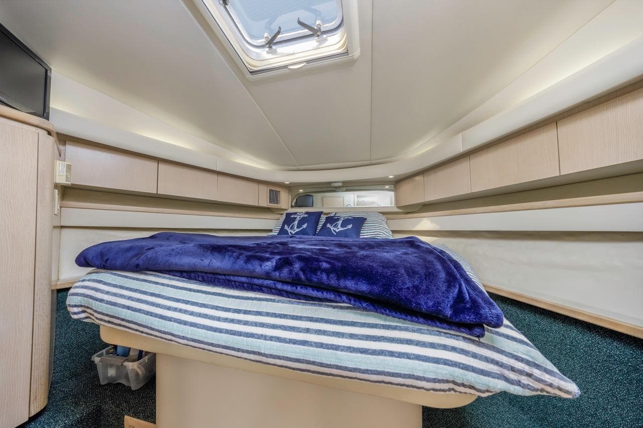 Luxurious cabin interior of 2000 Tiara Yachts 4000 Express with cozy bedding and skylight.