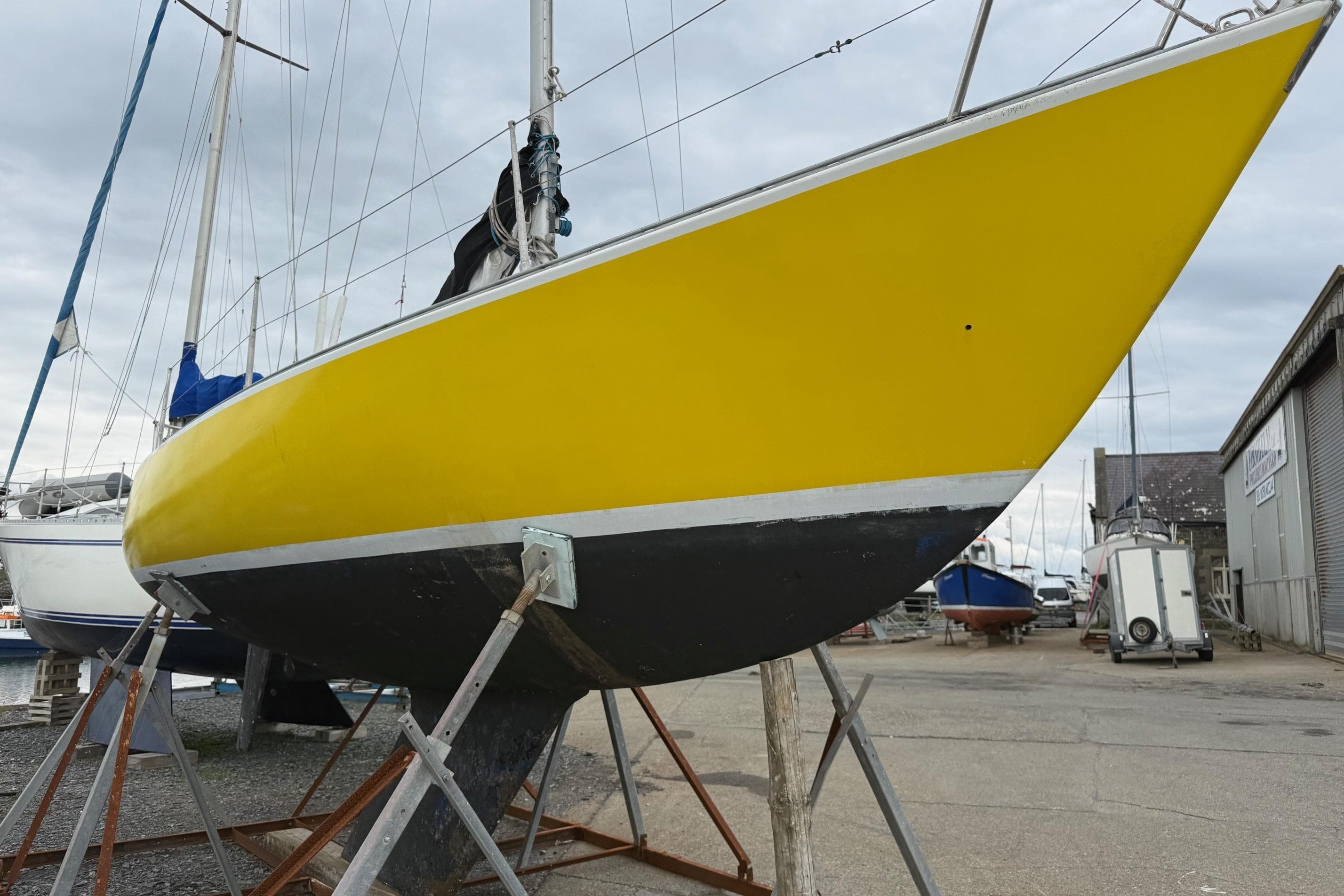 Yellow 1980 Sadler 25 sailboat on stands in a boatyard.