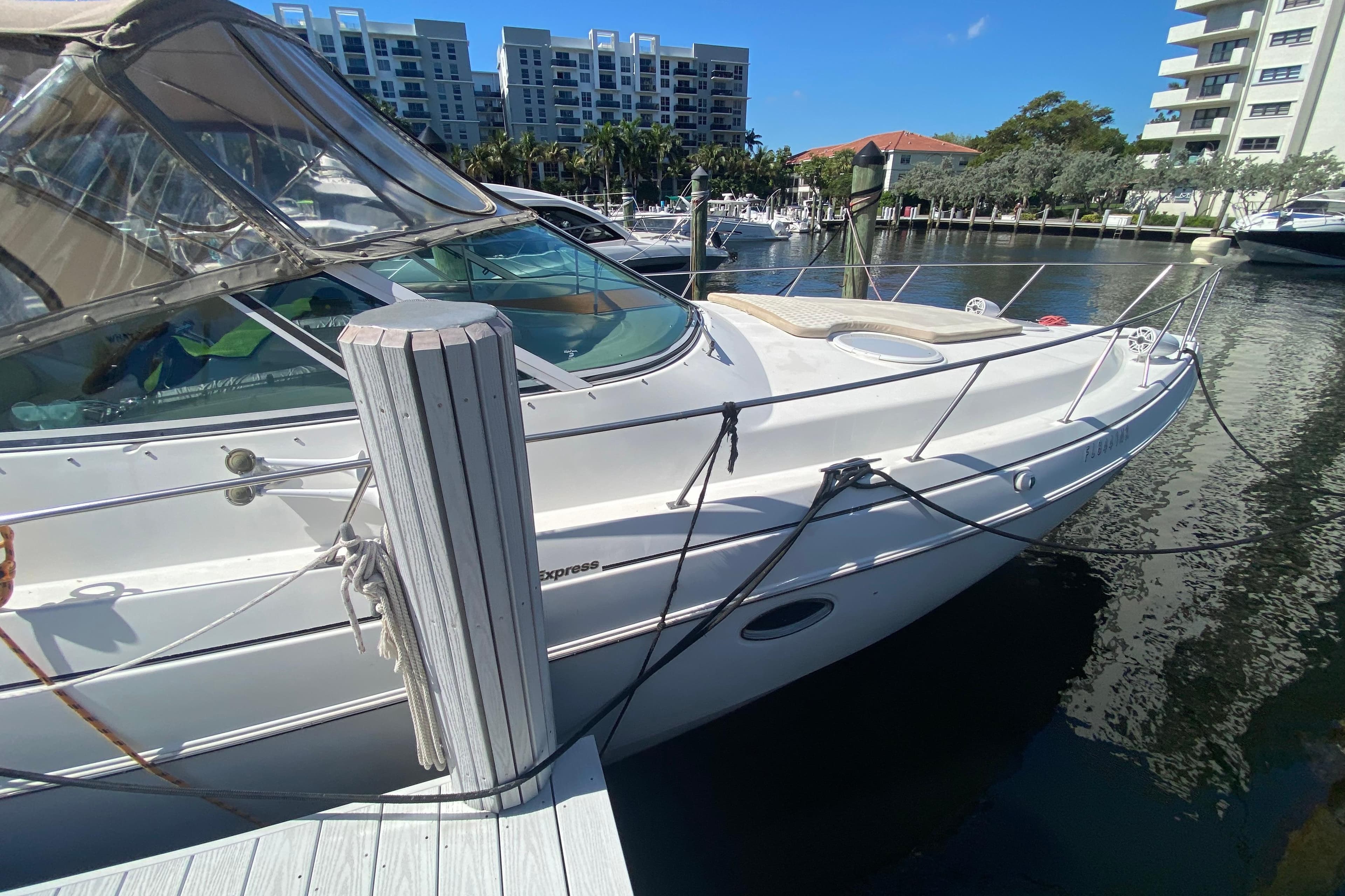 2002 Cruisers Yachts 3572 Express docked at marina, sunny day, waterfront buildings.