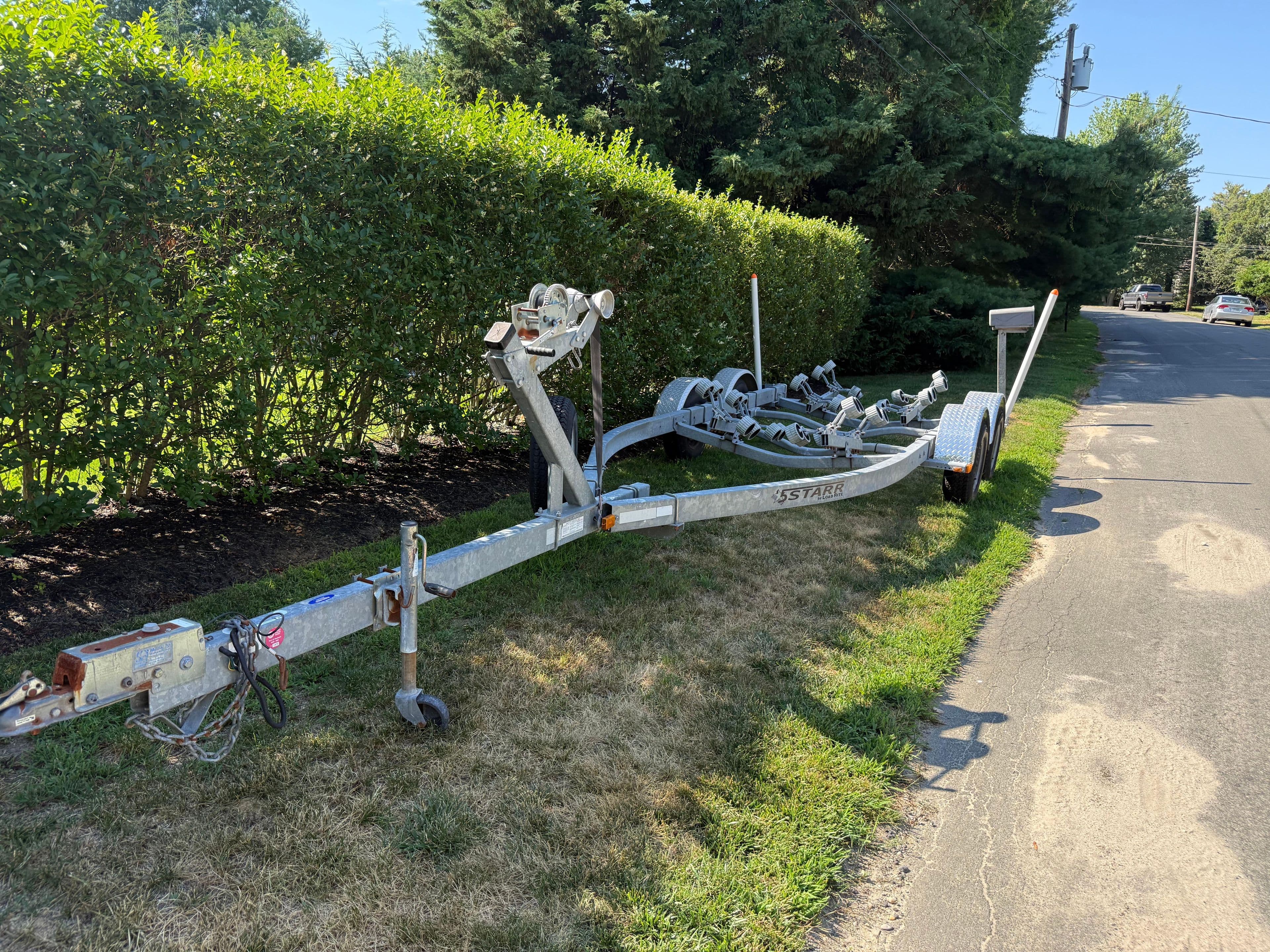 Trailer for 2008 Regal 2200 Bowrider parked on roadside grass.
