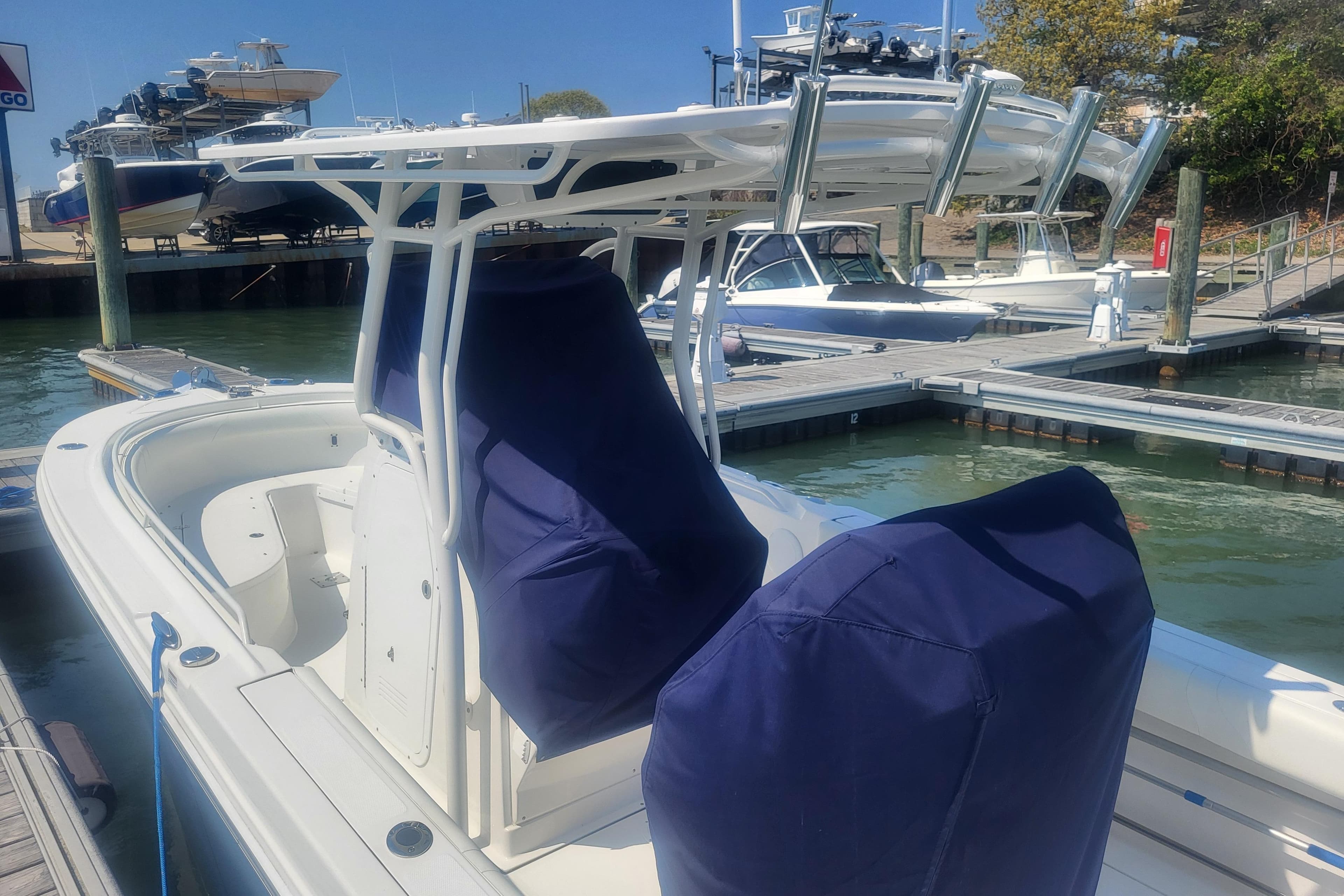 2022 Edgewater 245CC boat docked, featuring covered seats and a T-top, in a marina setting.