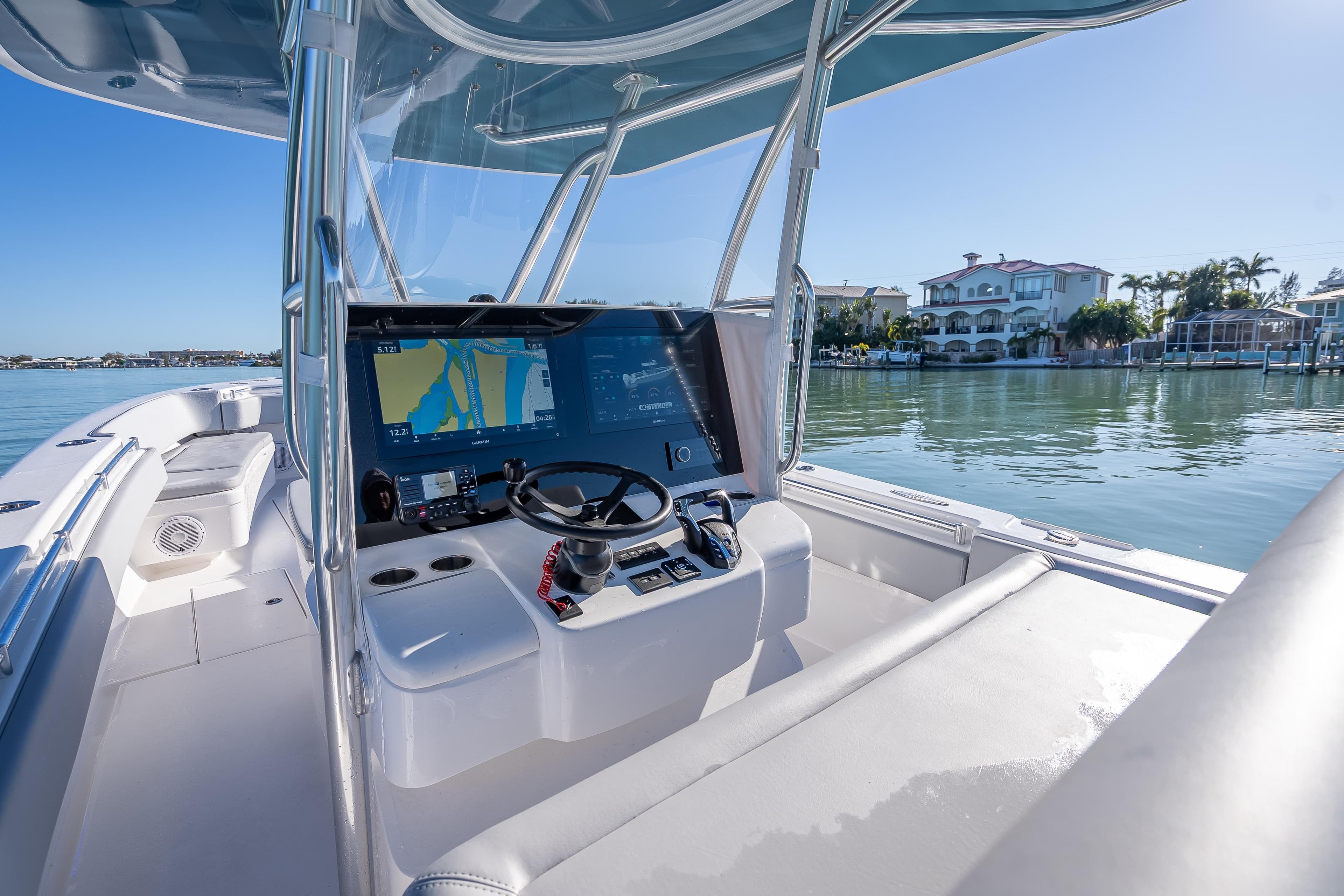 2026 Contender 35 ST boat cockpit with advanced navigation system, docked near waterfront homes.