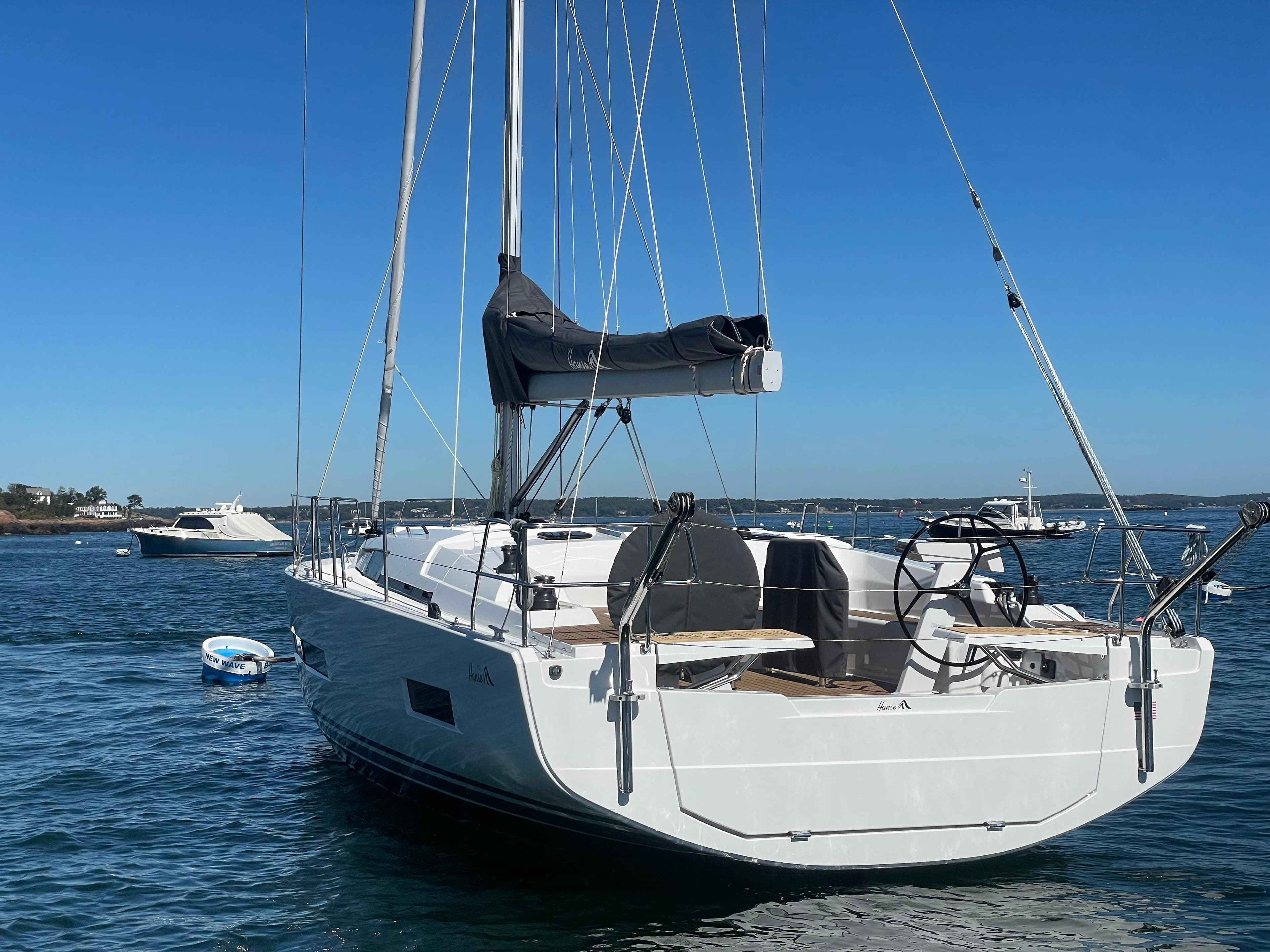 2024 Hanse 410 sailboat on calm water under clear blue sky.
