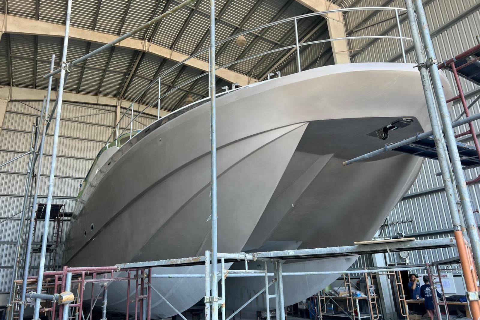 2025 Custom 65 Power Cat under construction in a shipyard, surrounded by scaffolding.