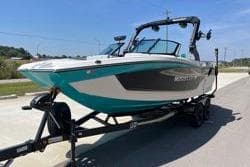 2025 MasterCraft XT22 boat on trailer, teal and black design, parked outdoors.