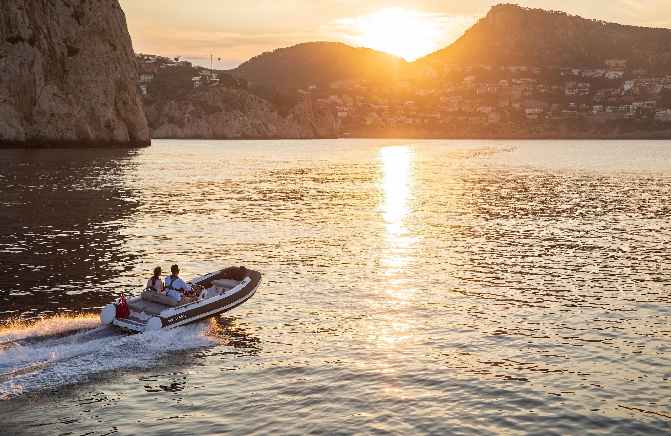 2025 Williams Jet Tenders Sportjet 435 cruising at sunset near rocky coastline.