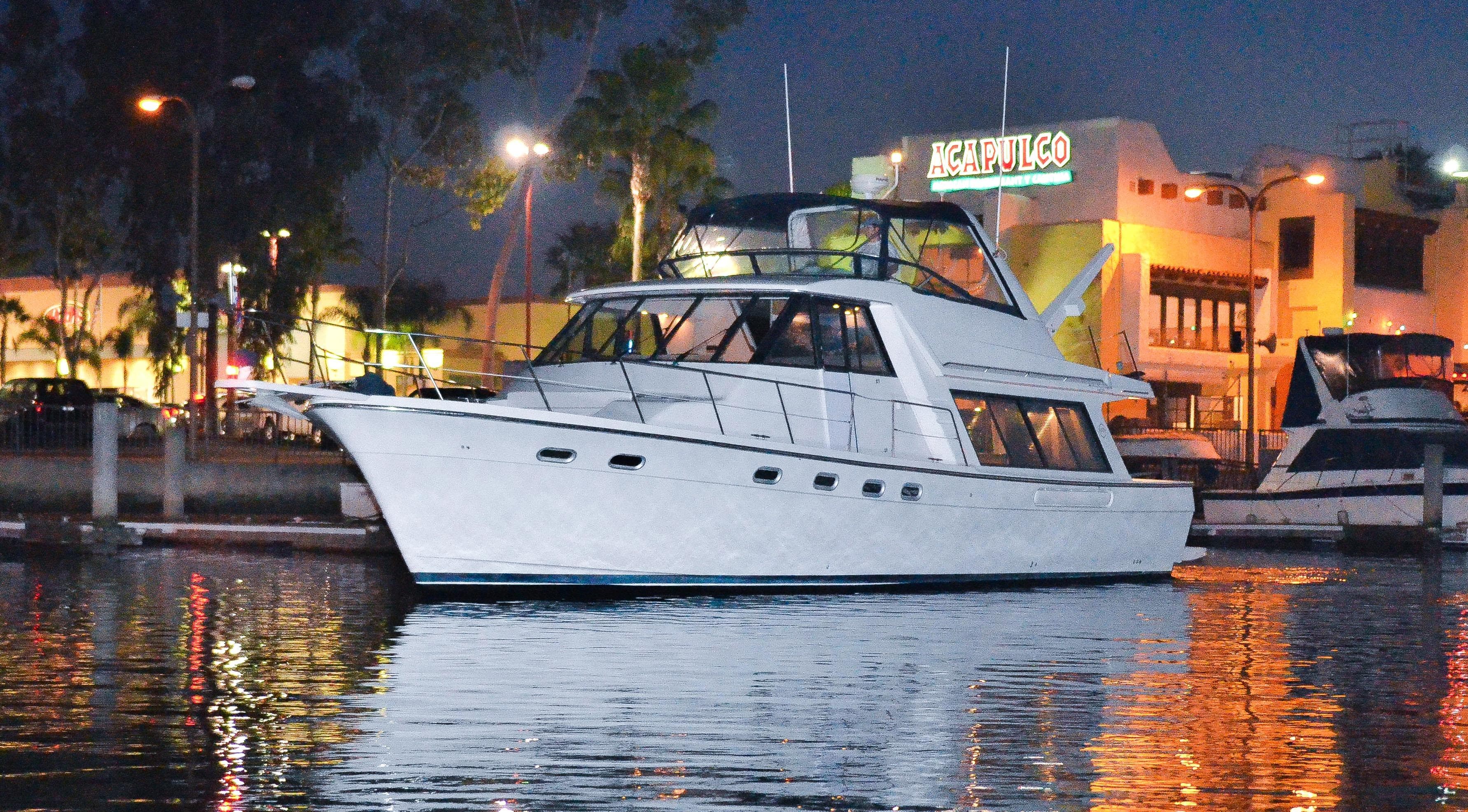2002 Bayliner 4788 Pilot House Motoryacht docked at night, reflecting on calm water.