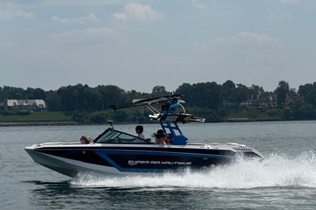 2018 Nautique Super Air Nautique GS22 speeding on a lake with passengers onboard.