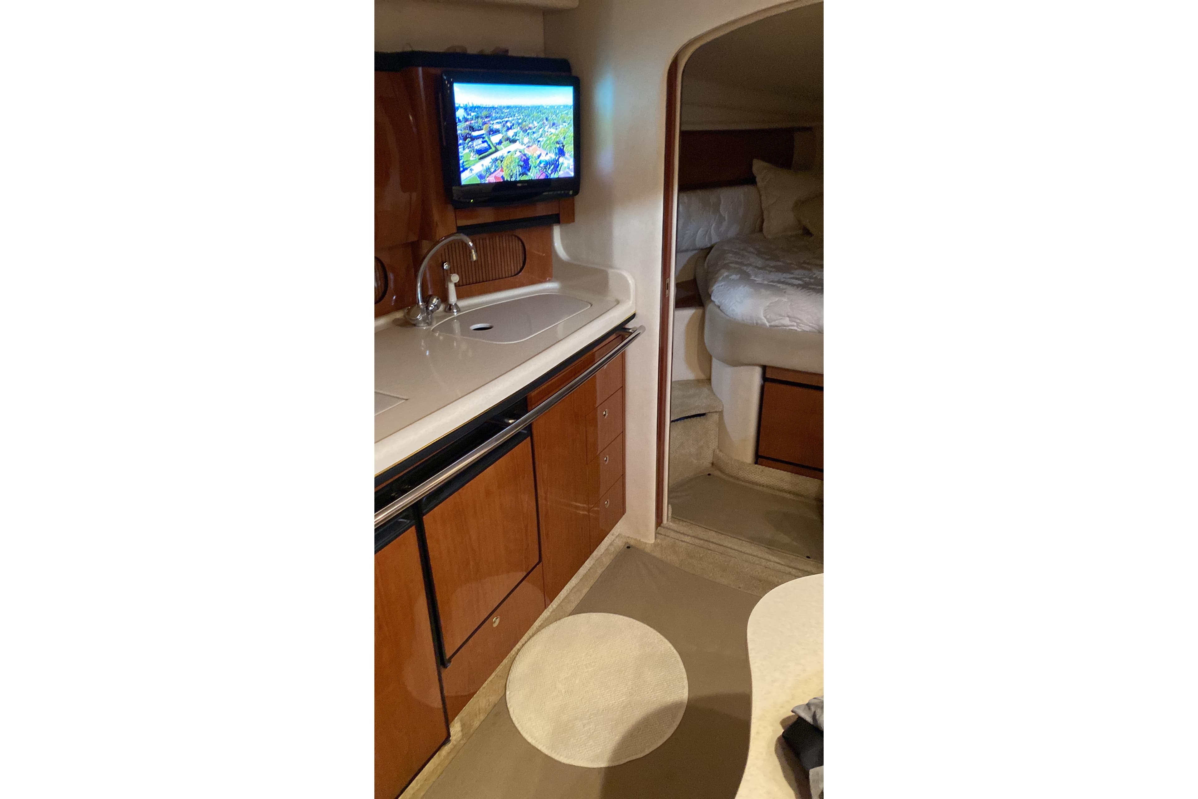 Interior of 2002 Sea Ray 360 Sundancer yacht with kitchenette and cozy sleeping area.
