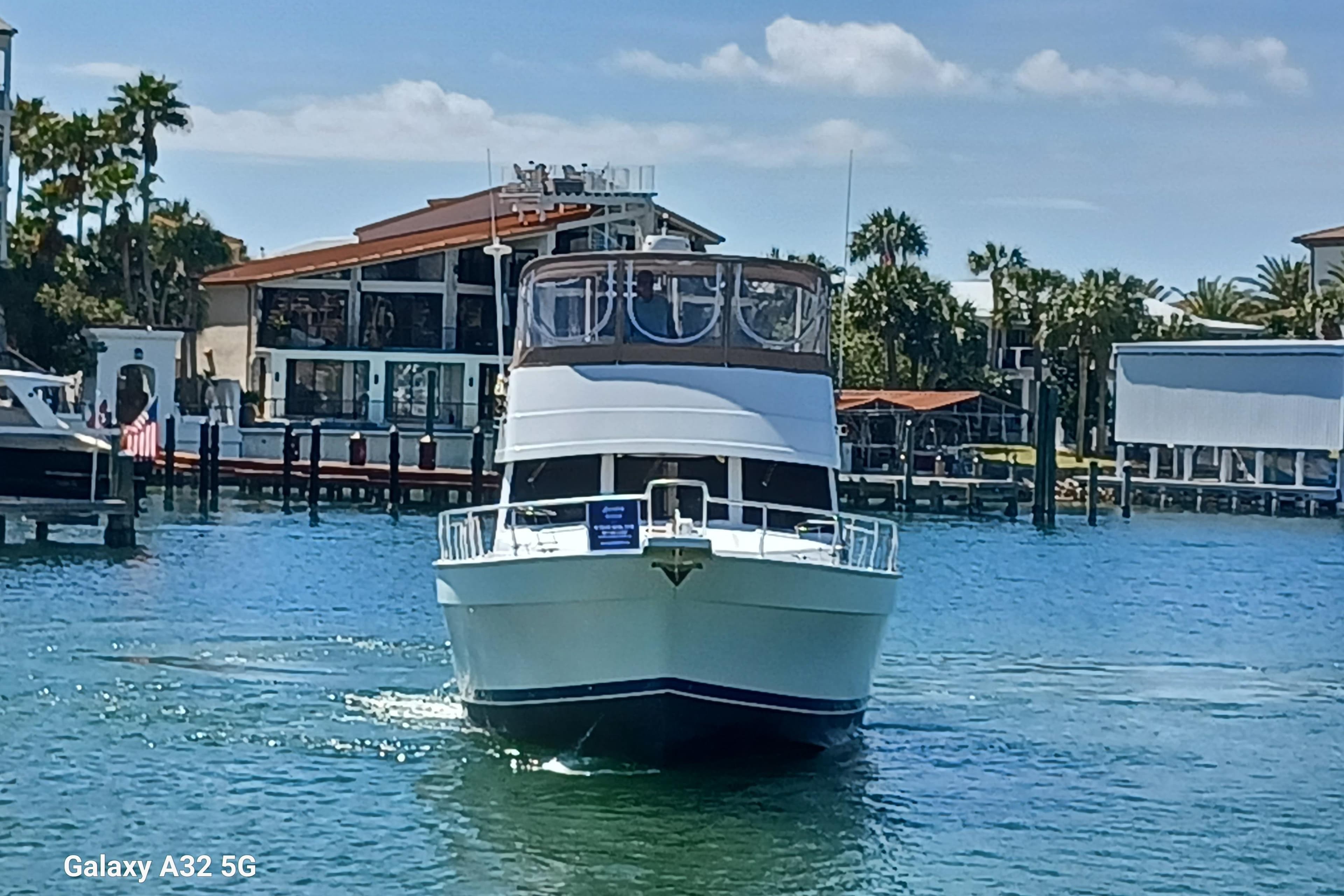 1999 Mainship 43 Trawler Aft Cabin cruising in a marina with waterfront homes.