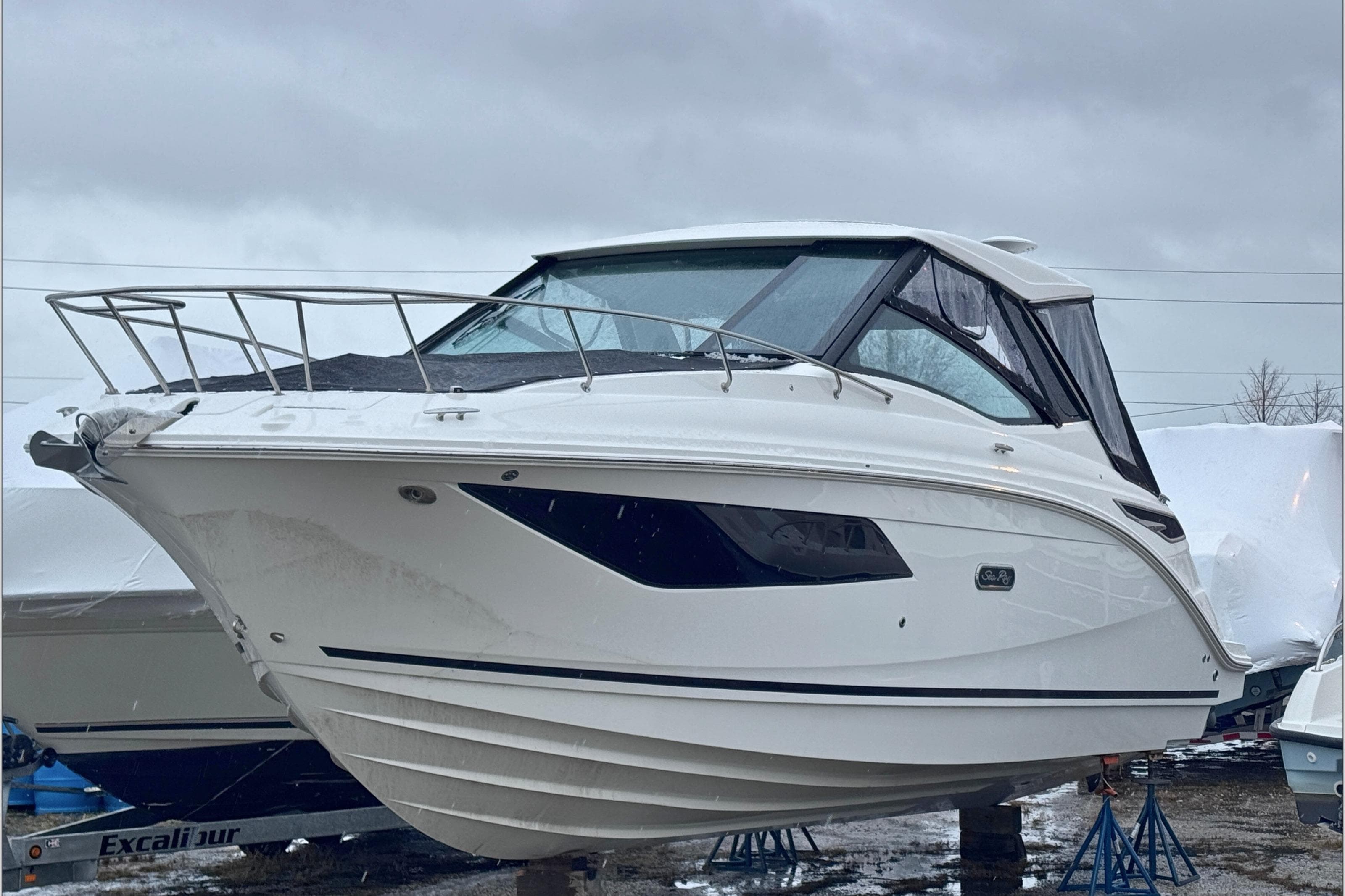 2025 Sea Ray Sundancer 320 boat on stands, overcast sky background.