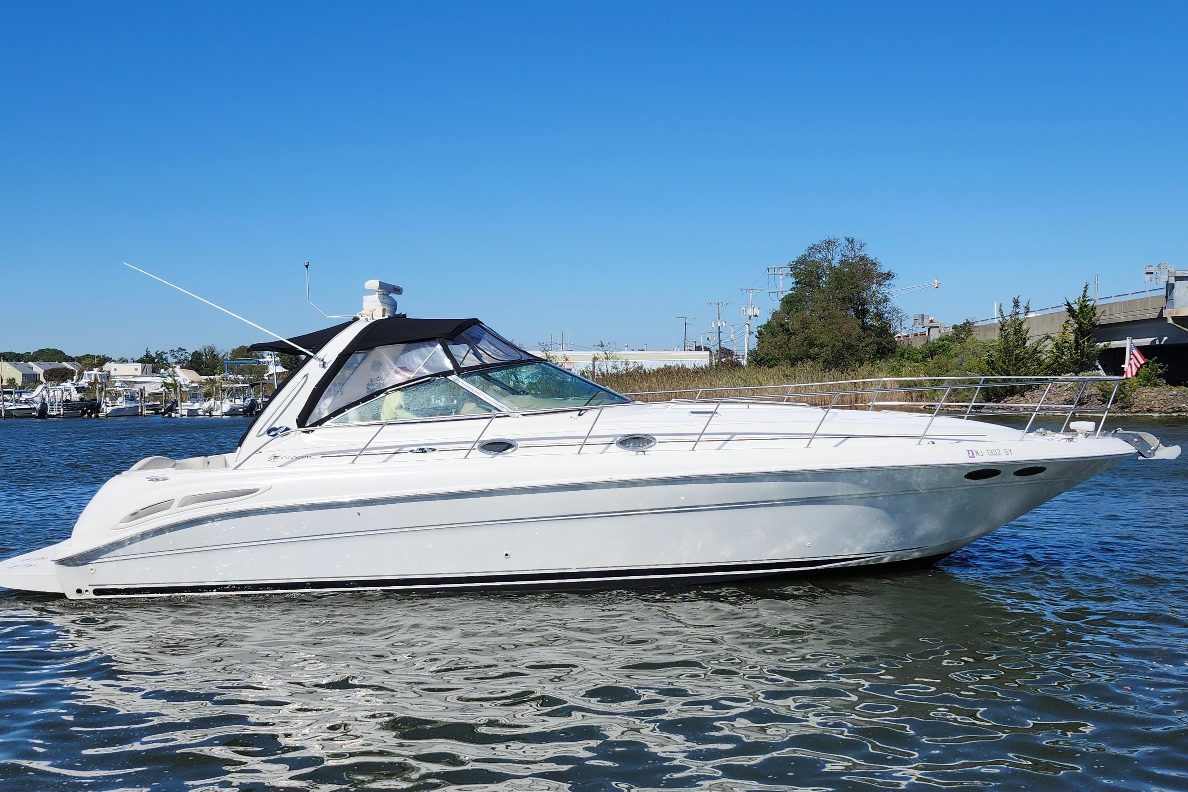 2002 Sea Ray 410 Sundancer yacht on calm water under clear blue sky.