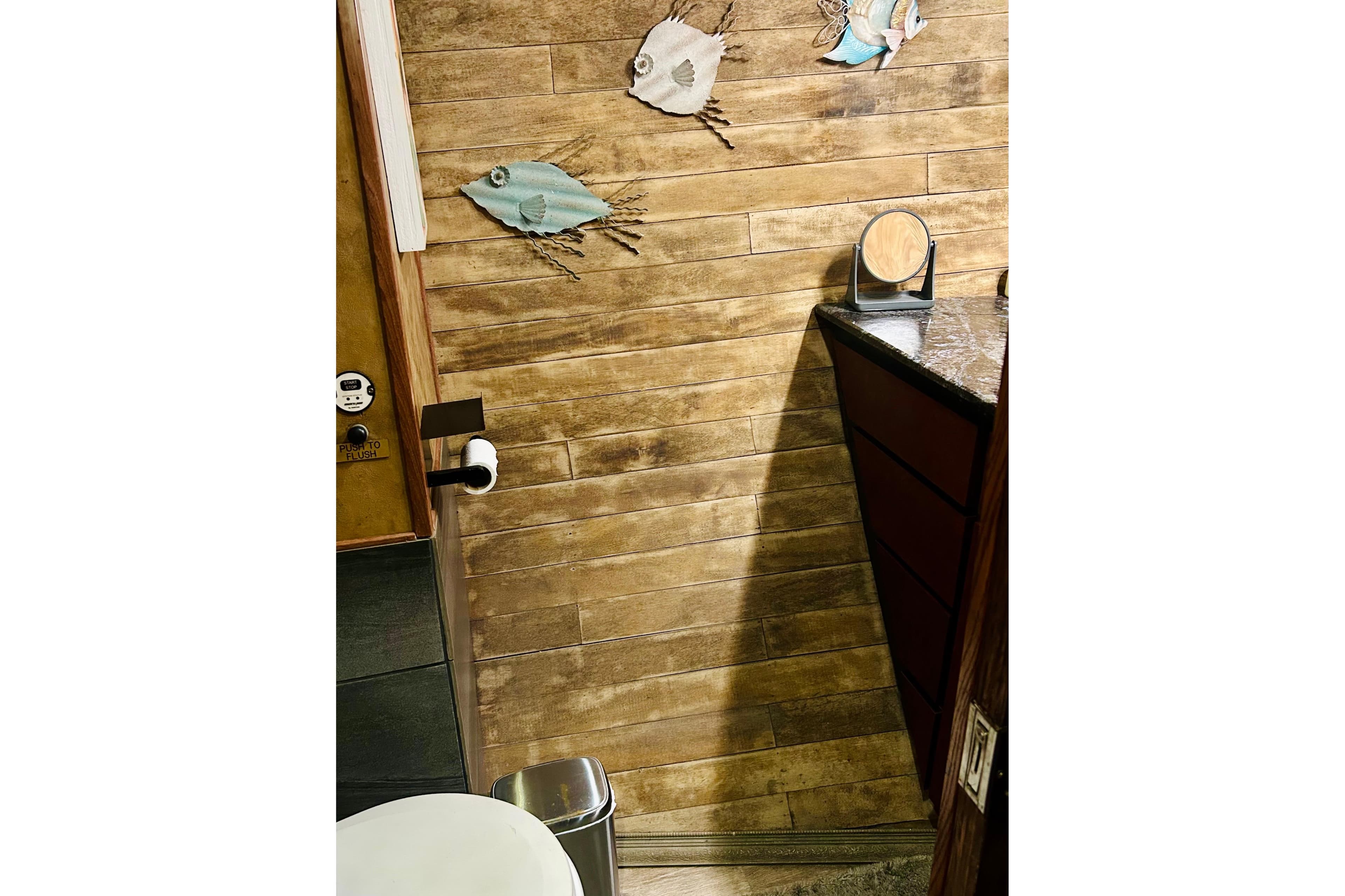 Wood-paneled bathroom with fish decor in a 1977 Custom Brigantine boat.