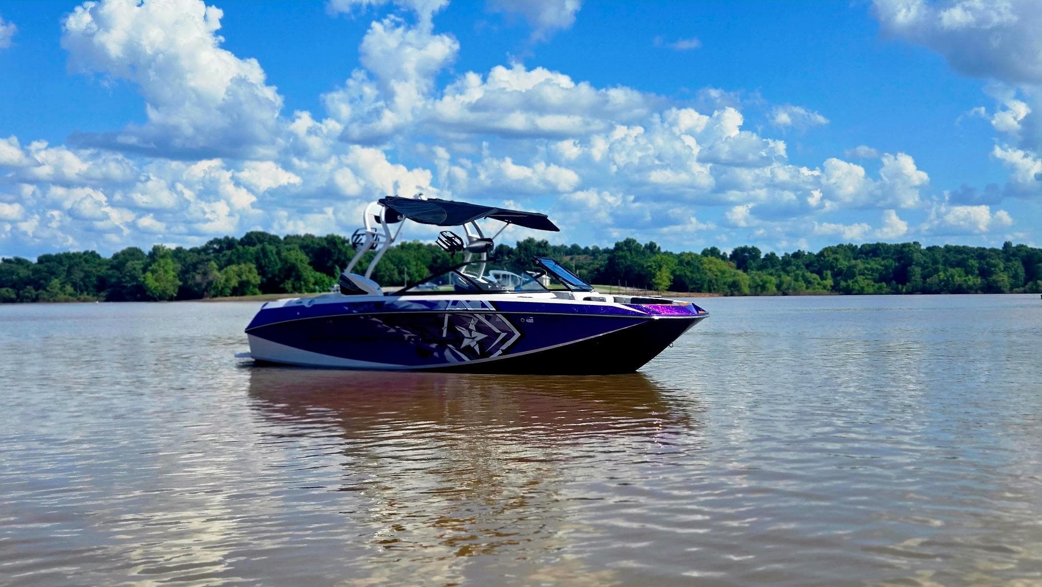 2014 Nautique Super Air Nautique G21 boat on calm lake under blue sky.