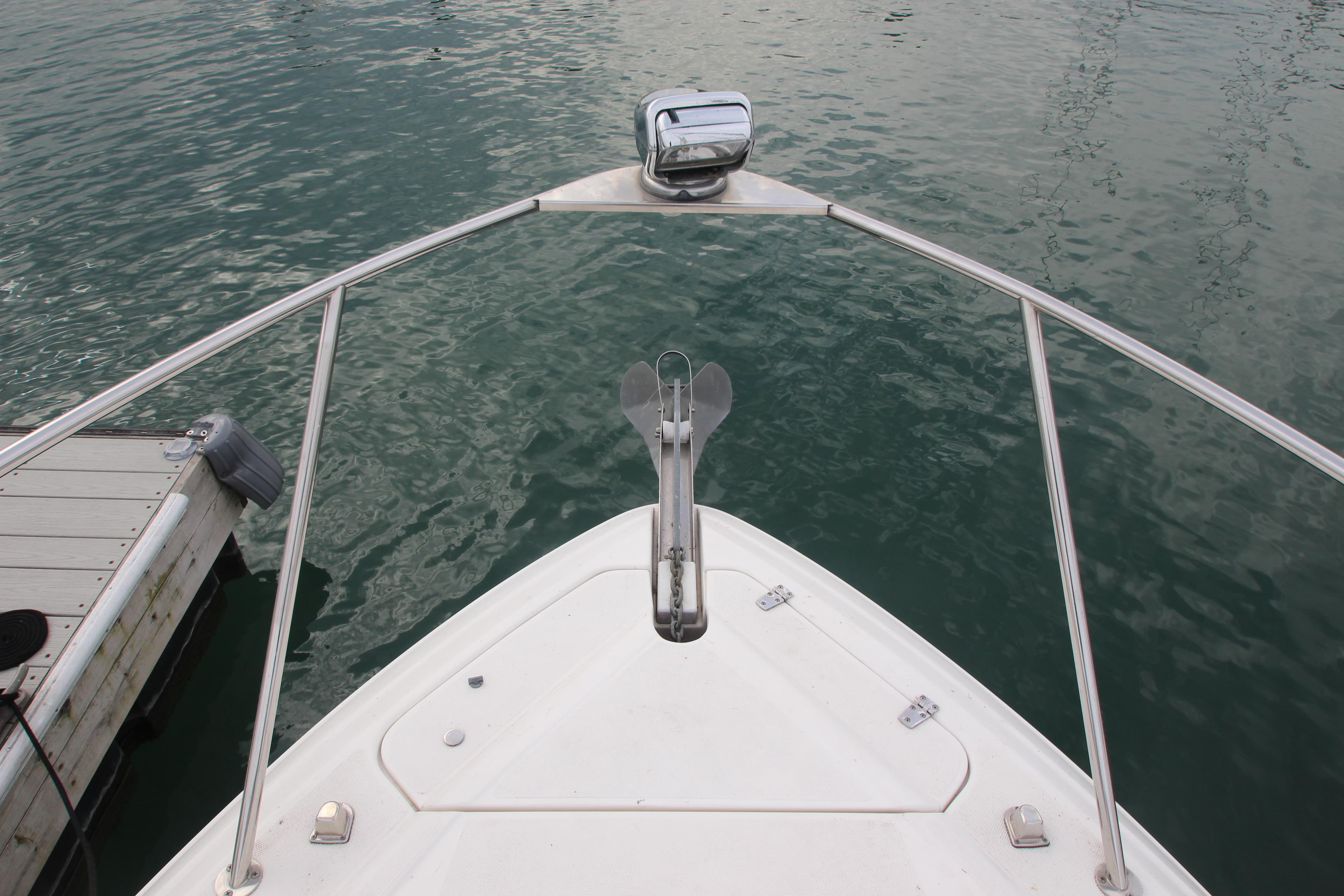 2008 Rinker 330 Express Cruiser bow with anchor, docked on calm water.