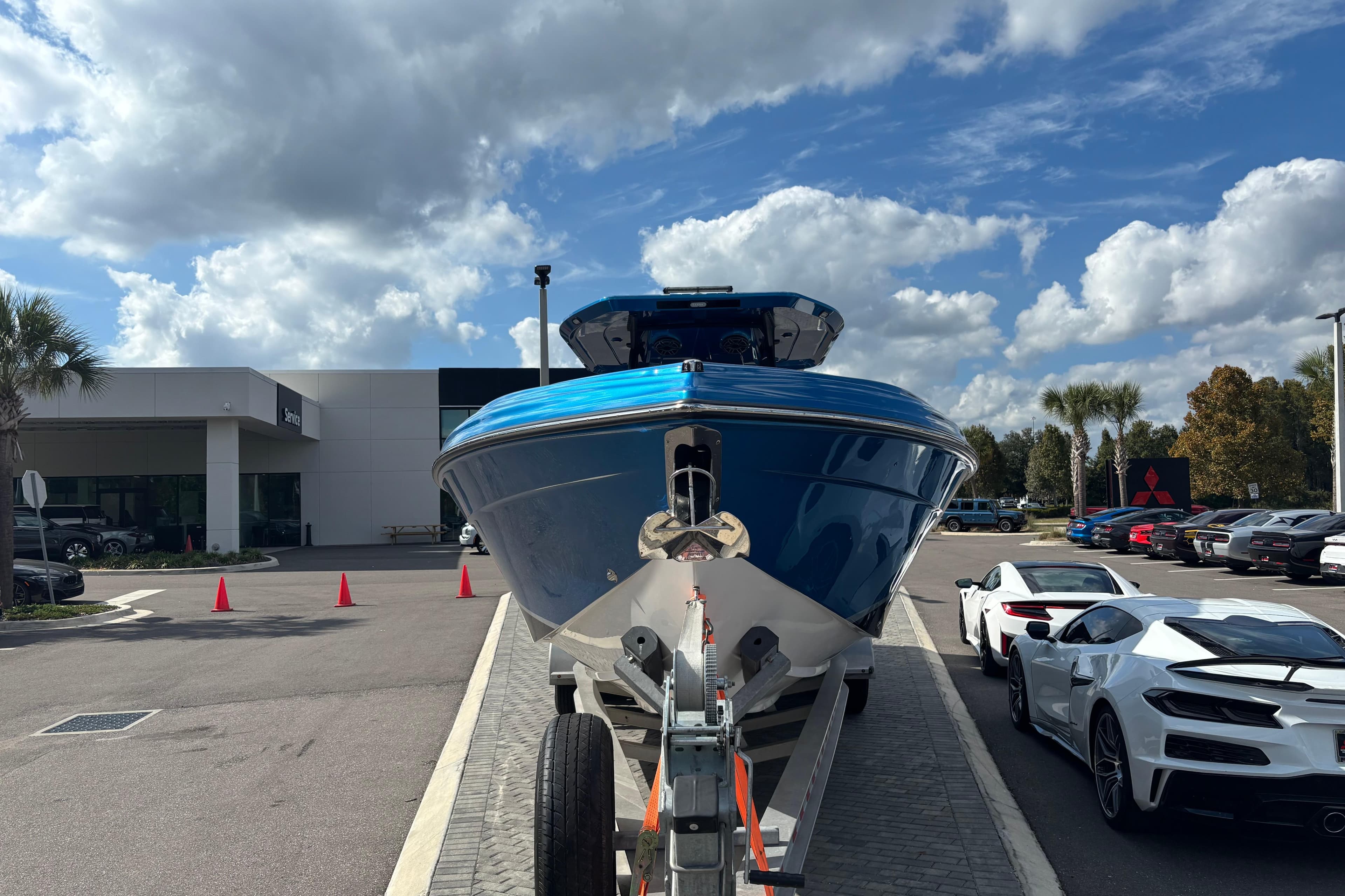 2024 GSX 36 boat on trailer at dealership, with sports cars and cloudy sky.