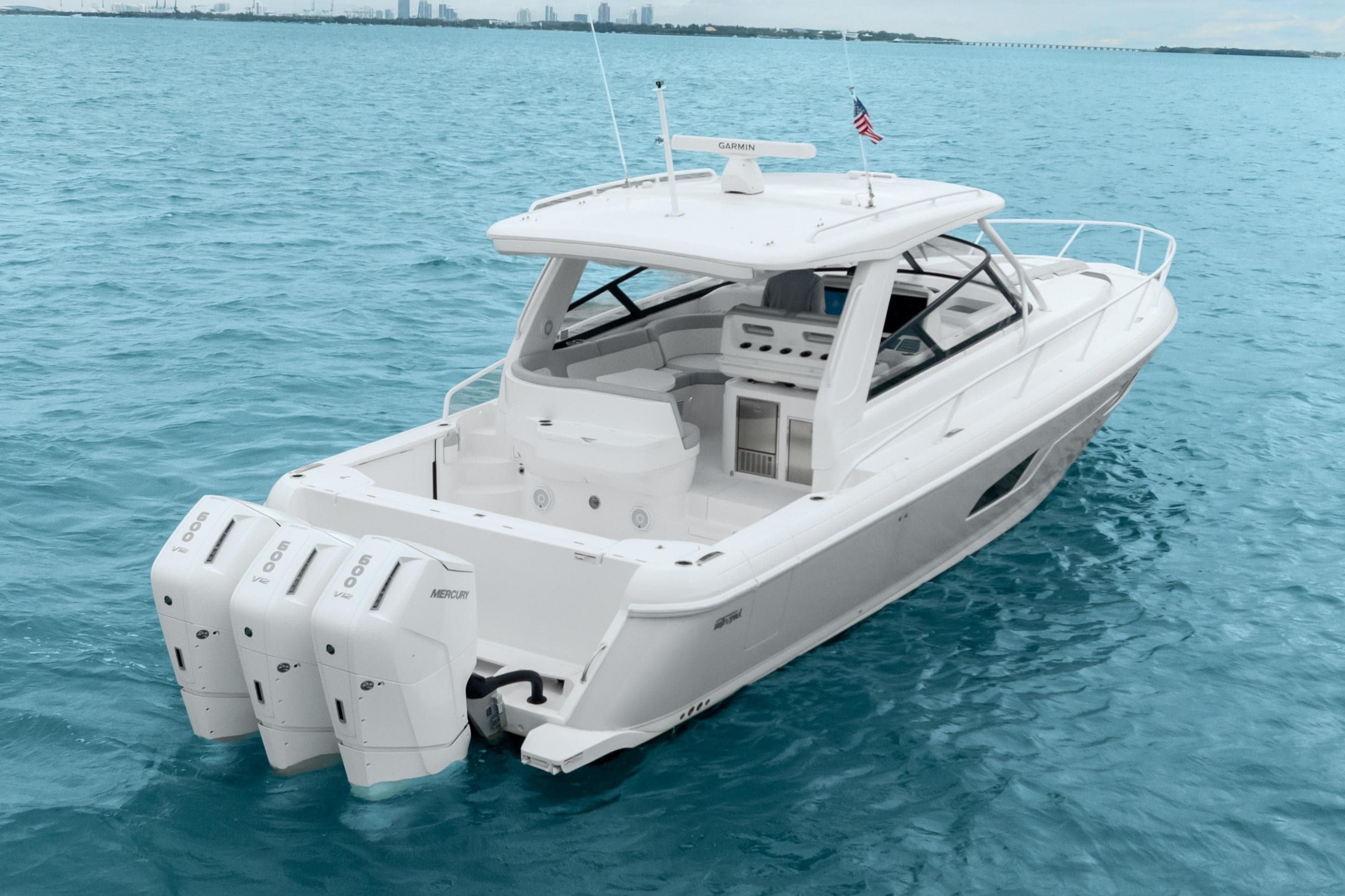 2024 Intrepid 477 Evolution boat on clear blue water, featuring triple Mercury engines.
