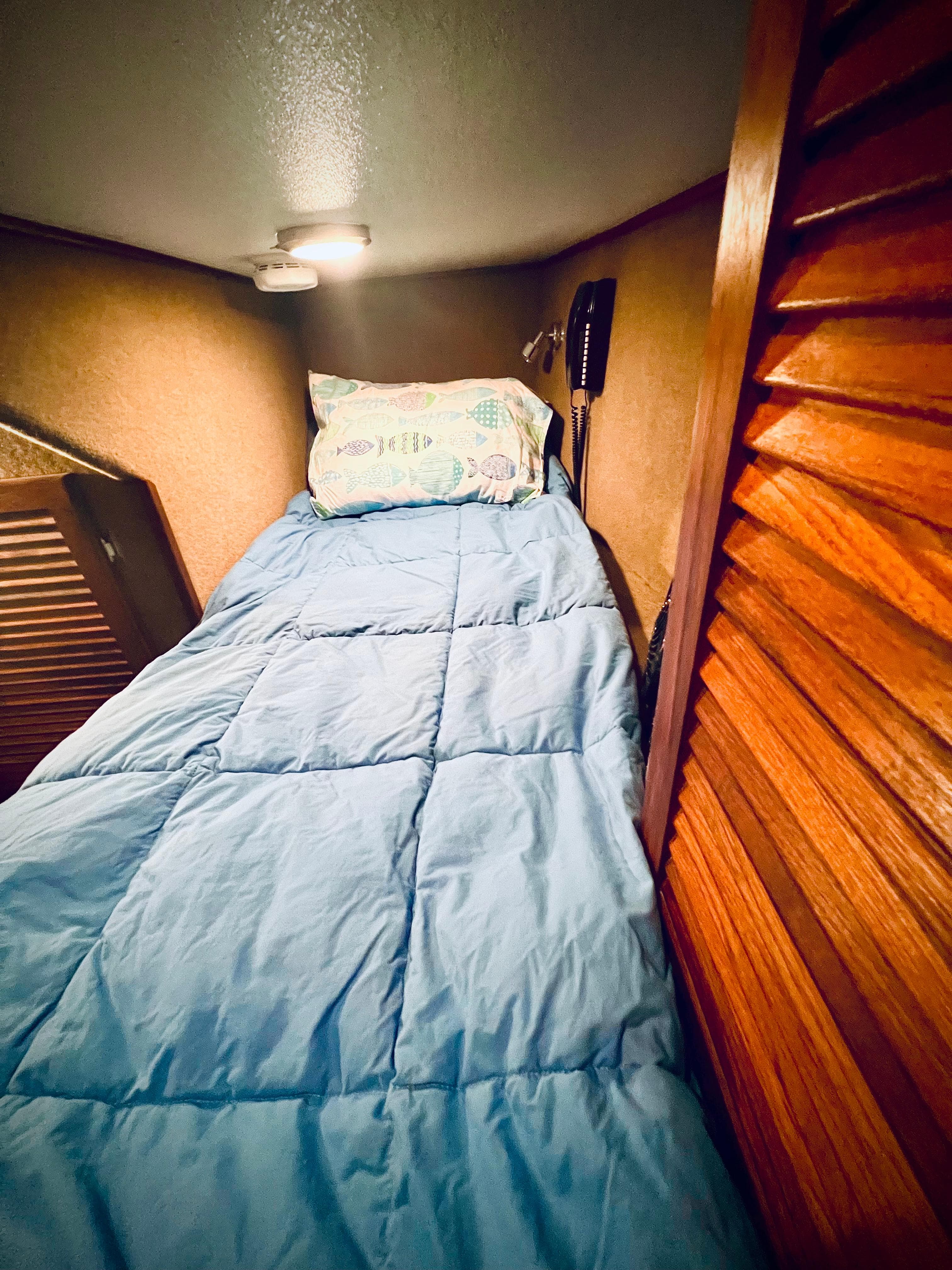 Cozy cabin bed in 2003 Peregrine 62 Custom yacht with blue bedding.