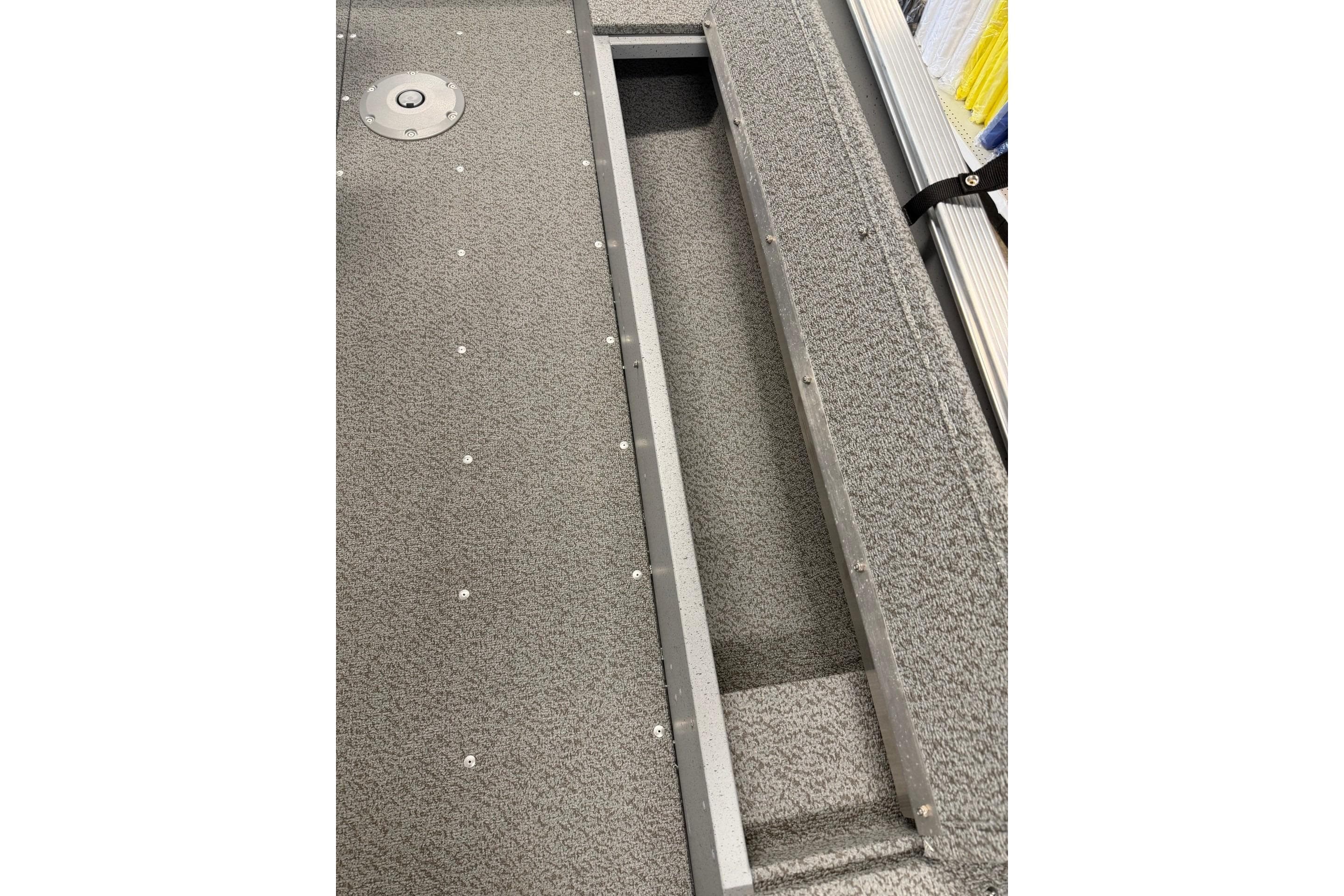 2026 Lund 1600 Fury Tiller boat interior with storage compartment and textured flooring.
