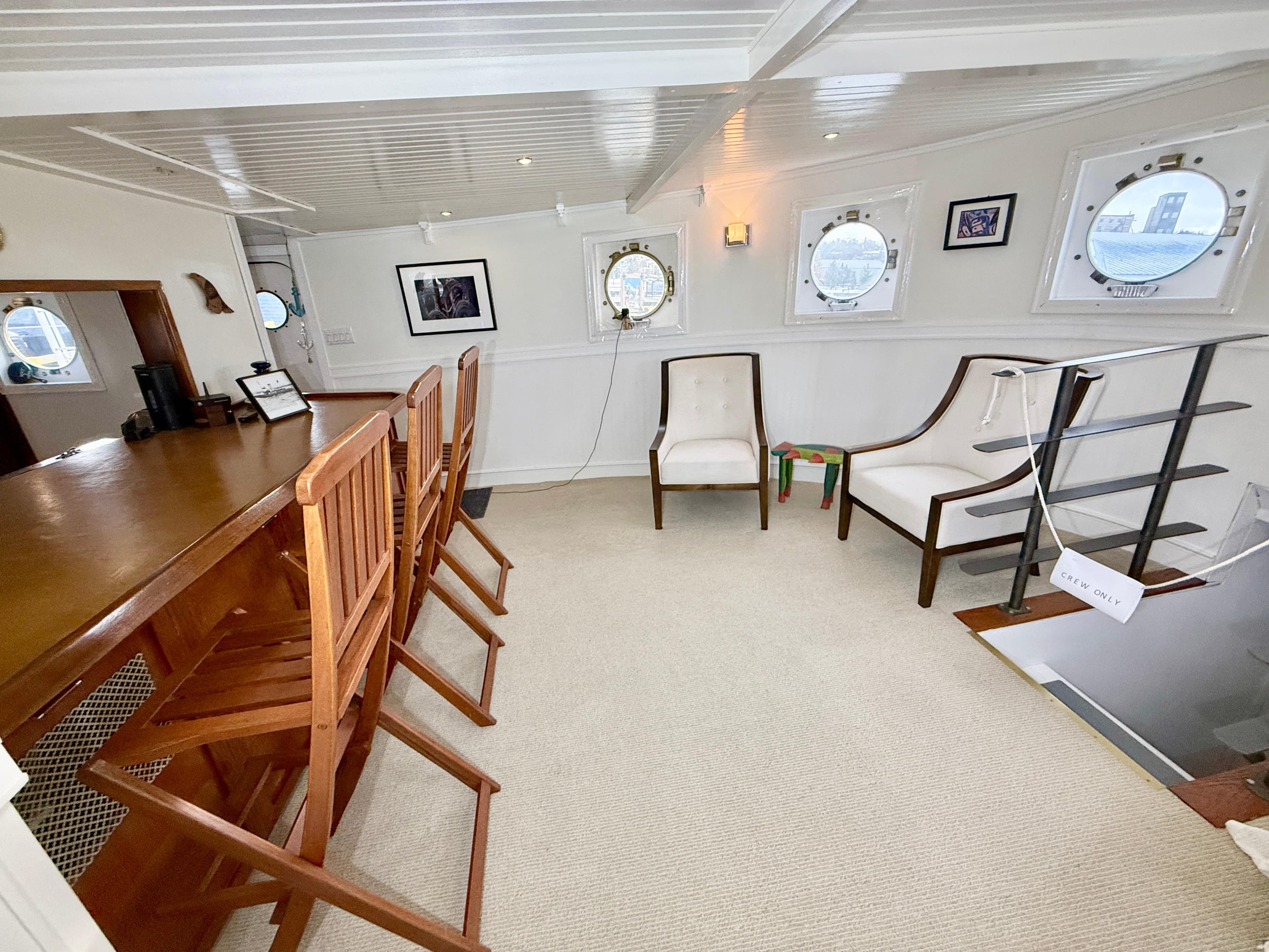 Interior of 1930 MV Prescotont Tug with bar, chairs, and porthole windows.