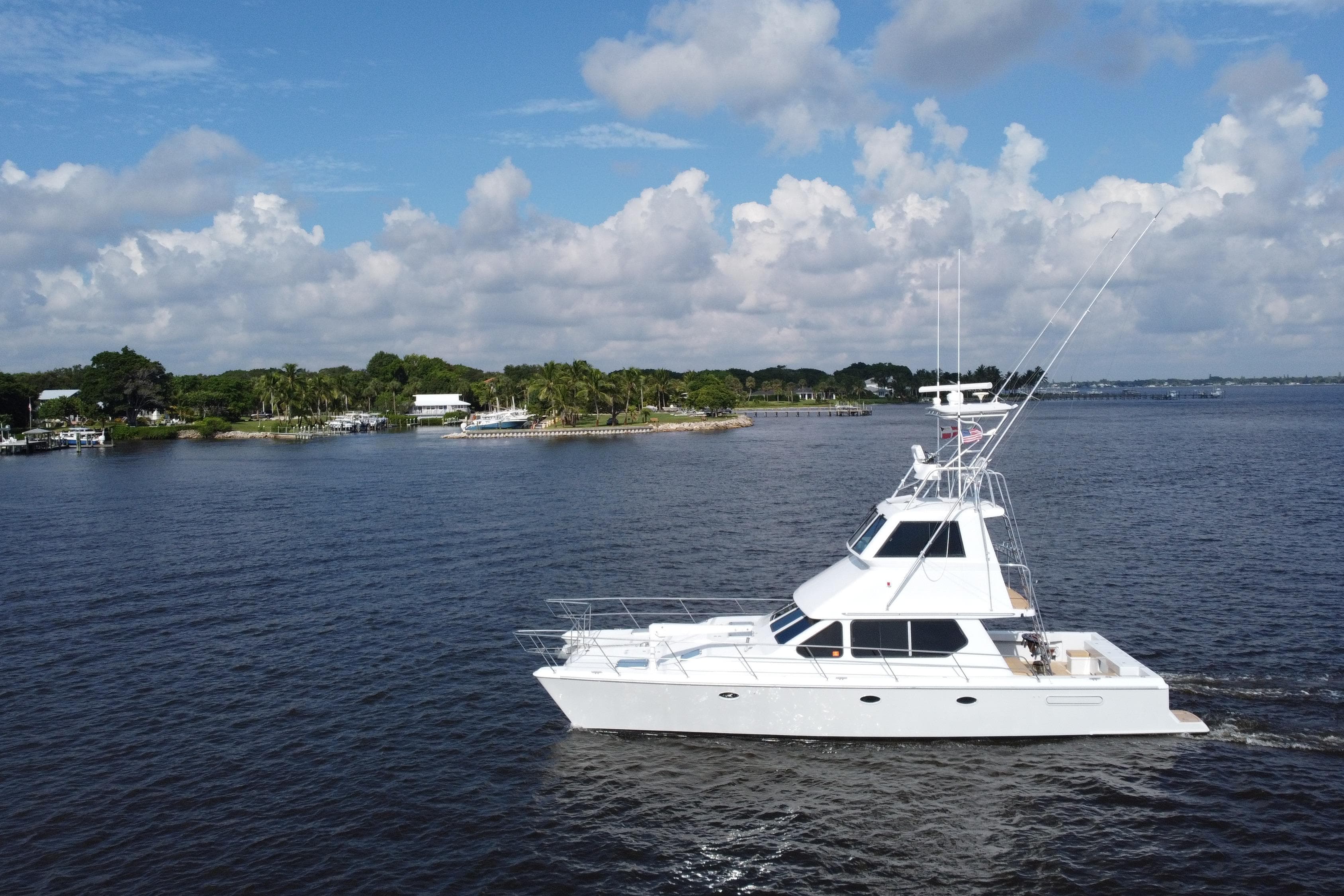 White Voyager 44 yacht cruising on a calm lake with a scenic shoreline.