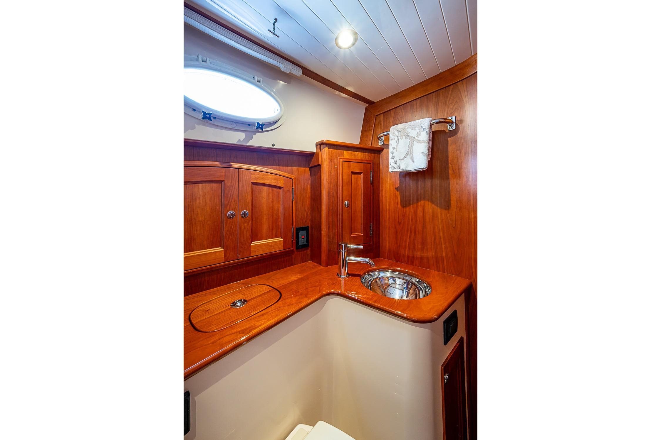 Luxurious wooden interior of 2021 Hinckley Talaria 43 yacht bathroom with sink and cabinets.