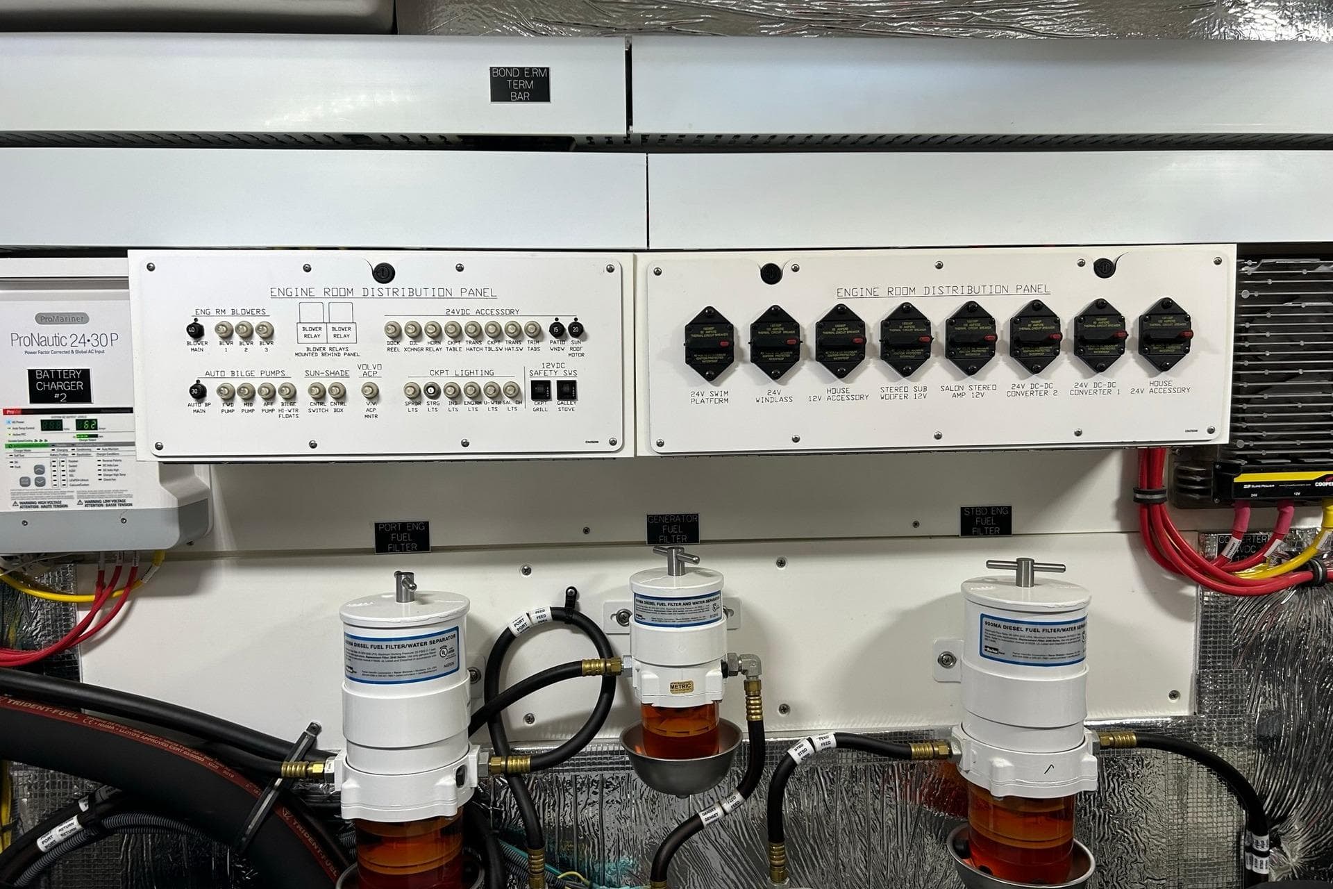 Engine room distribution panel of 2021 Cruisers Yachts 50 Cantius with battery charger and filters.